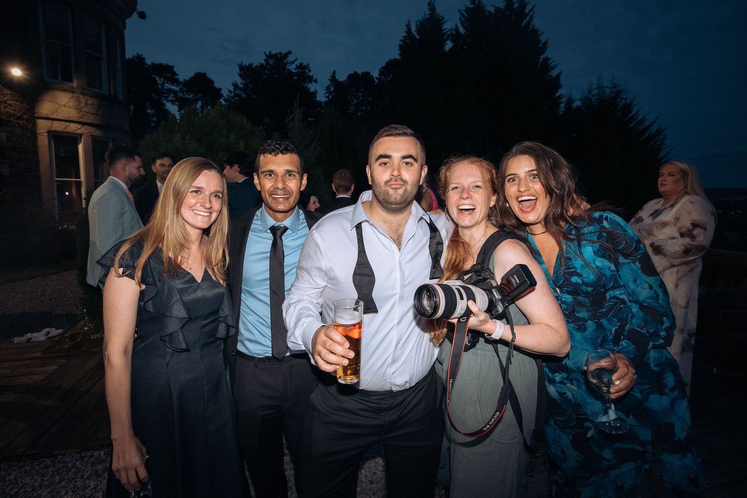 Professional photographers with cameras capturing evening event photos at an outdoor venue during twilight.