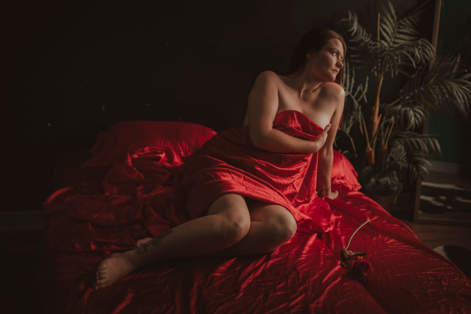 Dramatic neon pink and blue lighting illuminates a bedroom scene with someone relaxing on white bedding.