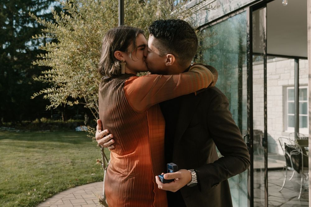 A couple shares an intimate embrace outdoors in front of a rustic building during a photo session.