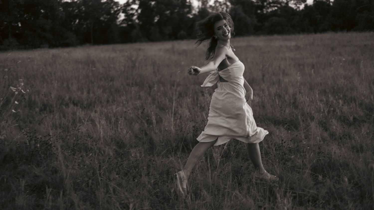 A sequence of black and white photos shows someone jumping and leaping gracefully across a grassy meadow at sunset.