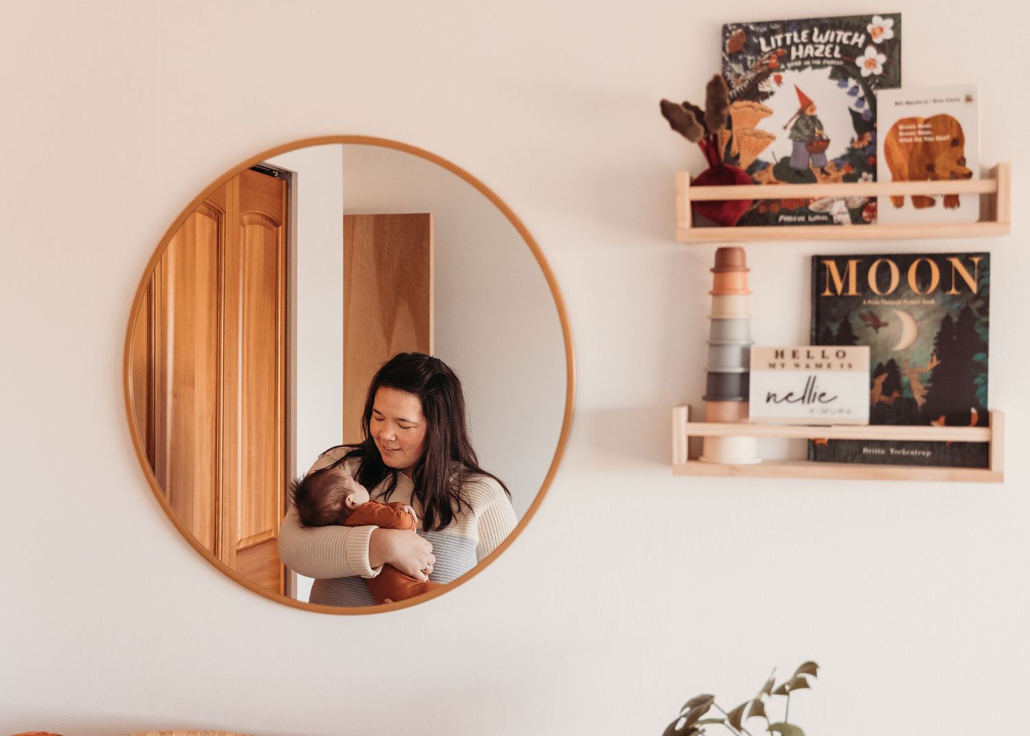 A series of oval mirrors mounted on a white wall reflect warm wooden accents and decorative elements in a modern home.