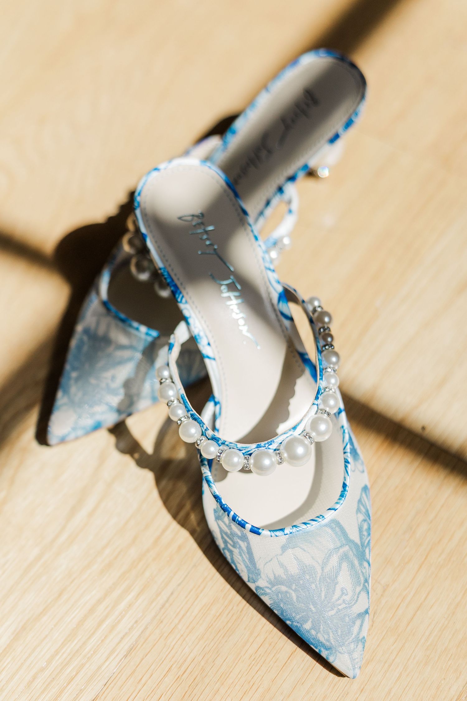 Light blue lace wedding shoes with delicate details on wooden floor.