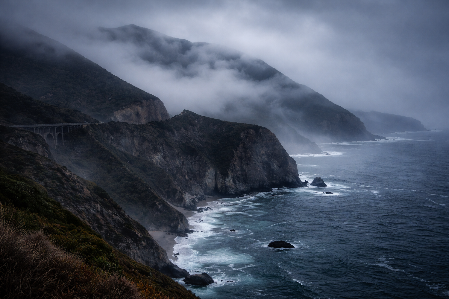 Dramatic coastal cliffs rise above crashing waves along a misty, rugged coastline under moody storm clouds.