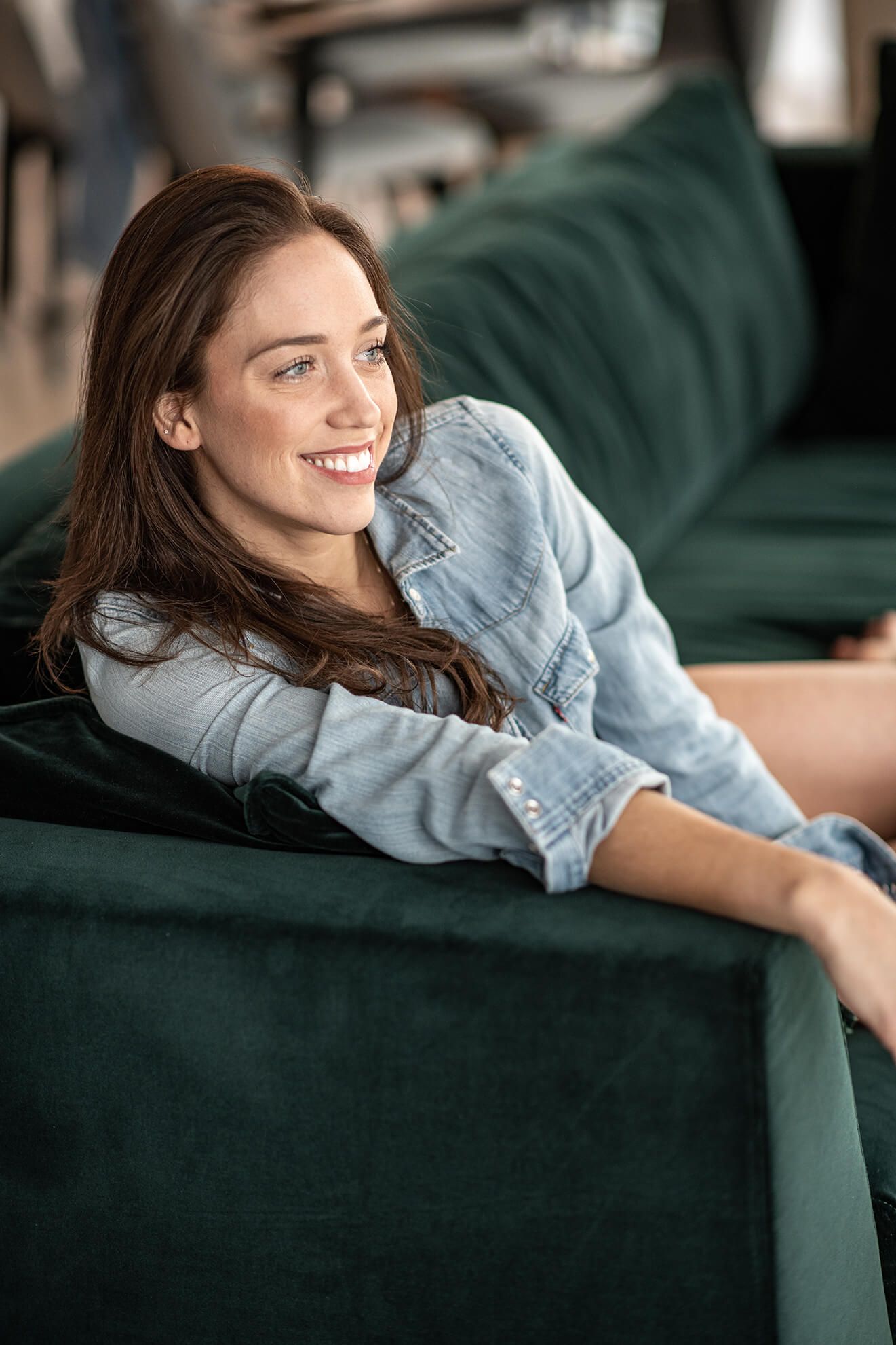 Relaxed lifestyle portraits on emerald green velvet couch showing casual denim style.