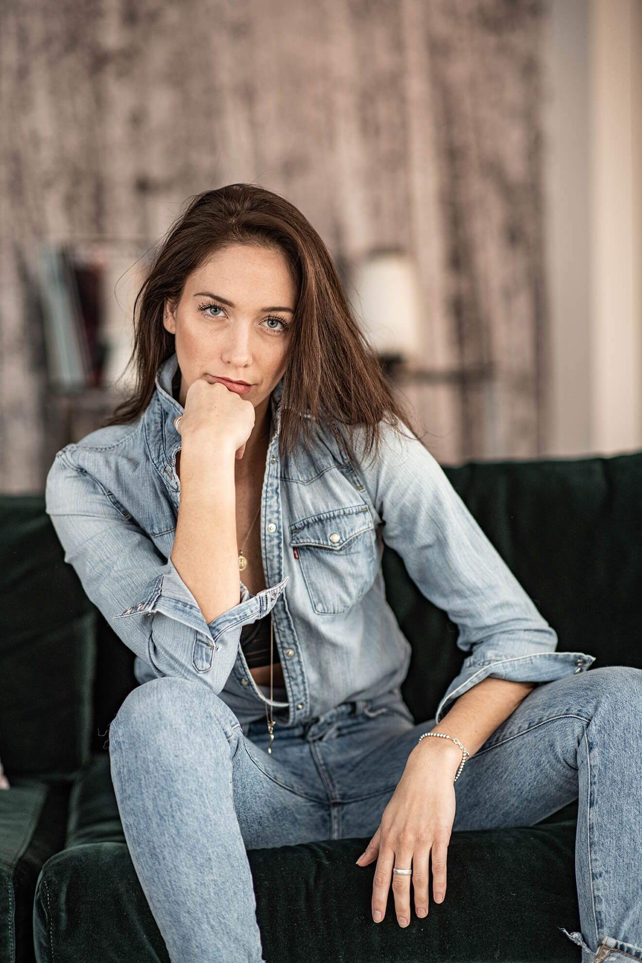 Casual portrait series of someone lounging on dark couch wearing denim jacket.