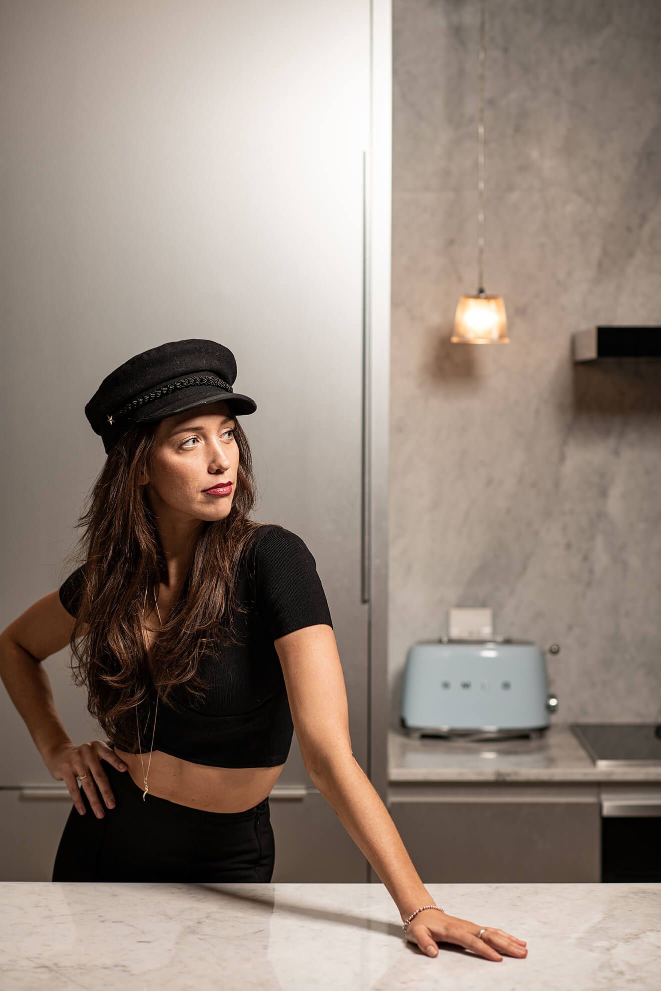 Stylish portraits featuring black outfit and newsboy cap on marble counter.