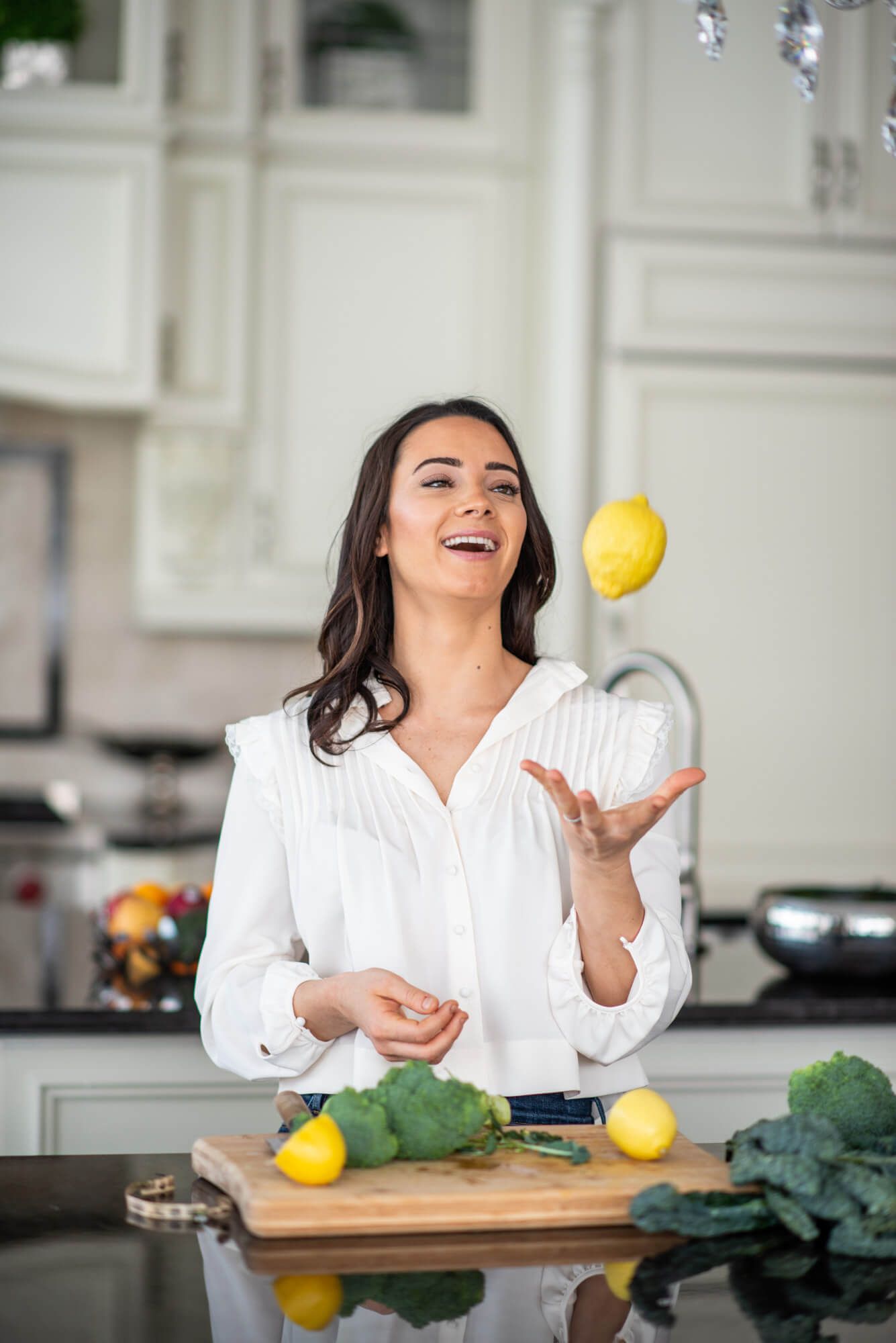 Playful cooking scene tossing lemon in bright white kitchen.