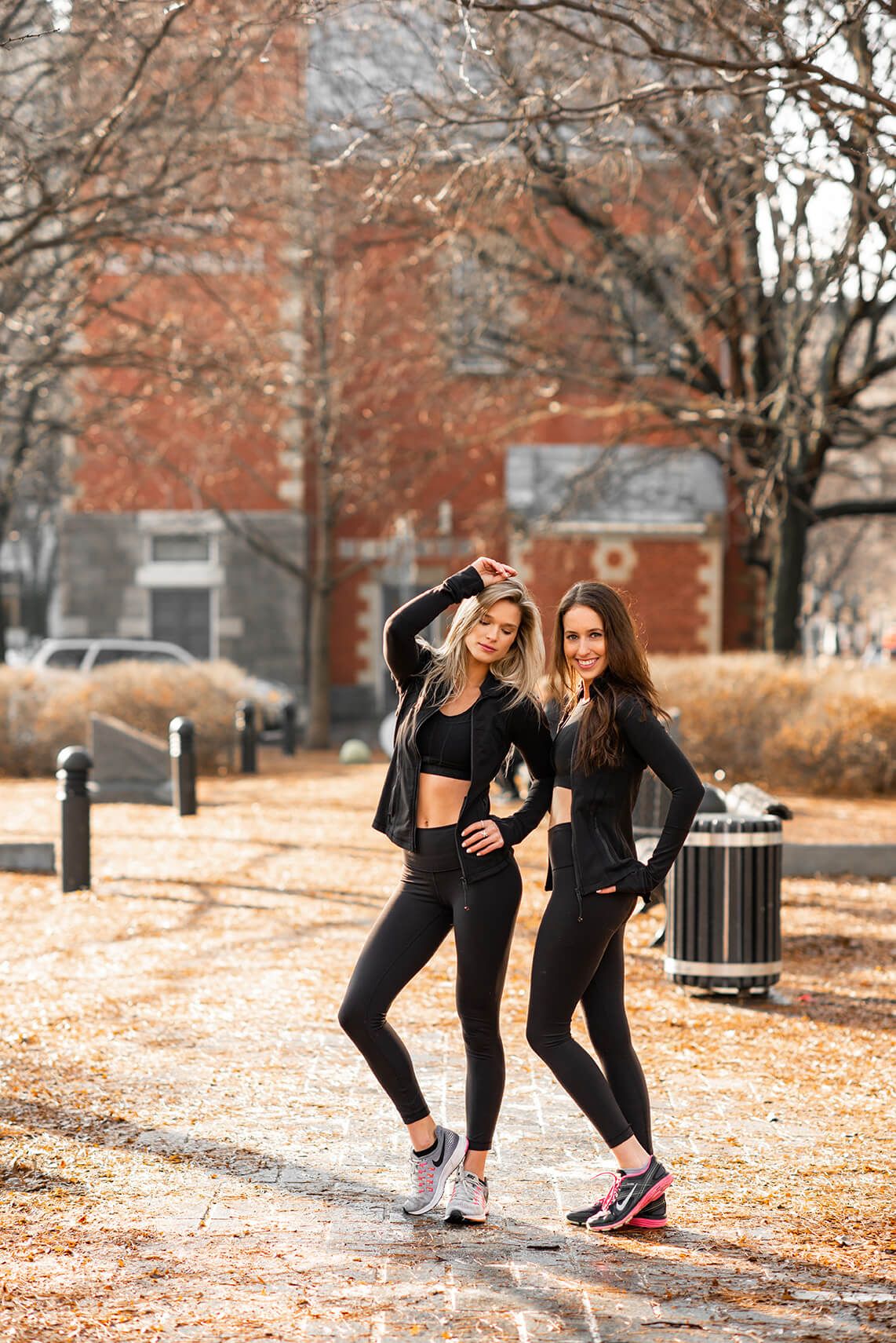 Athletic women in black workout attire posing on an autumn path.