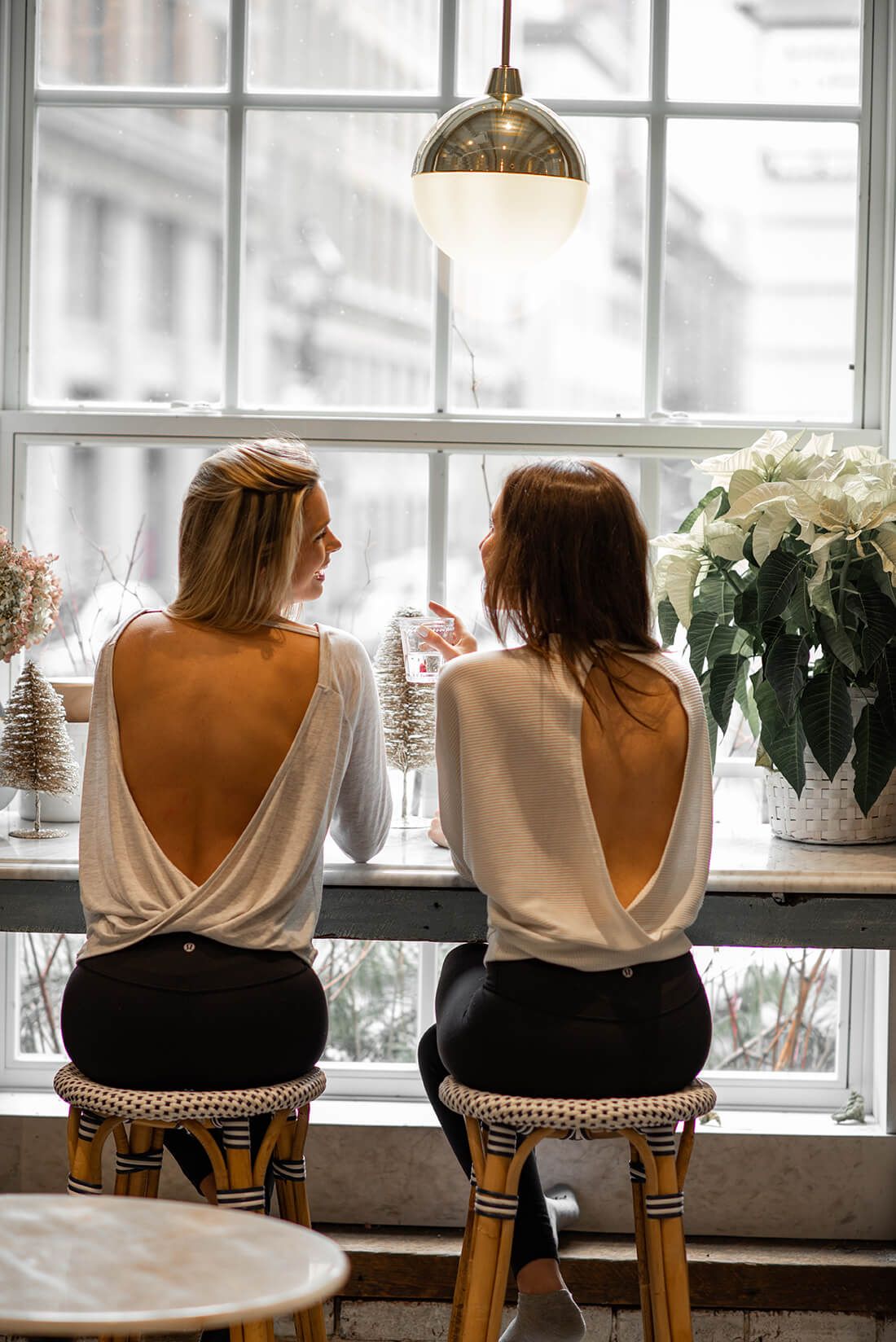 Two people seated on patterned chairs by window with white flowers and winter decorations.