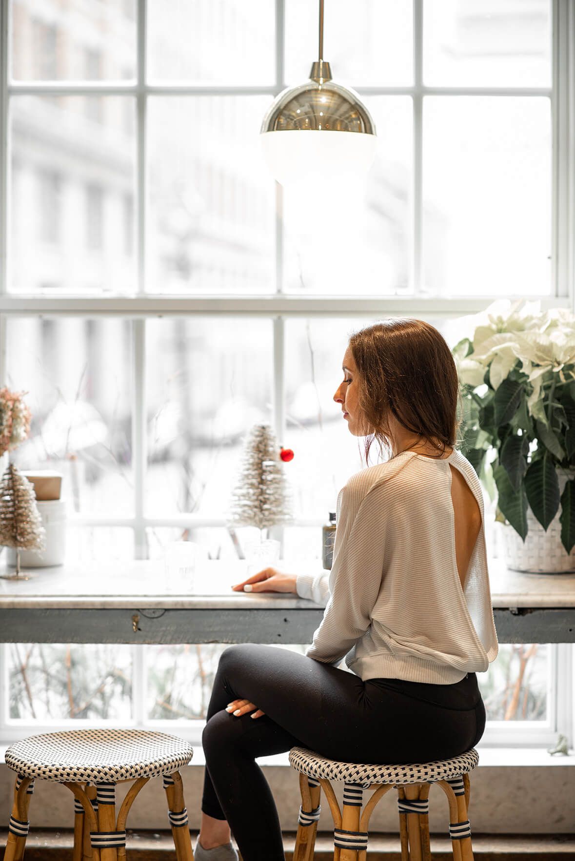 Two people sit side by side on chairs near a window with winter decorations.