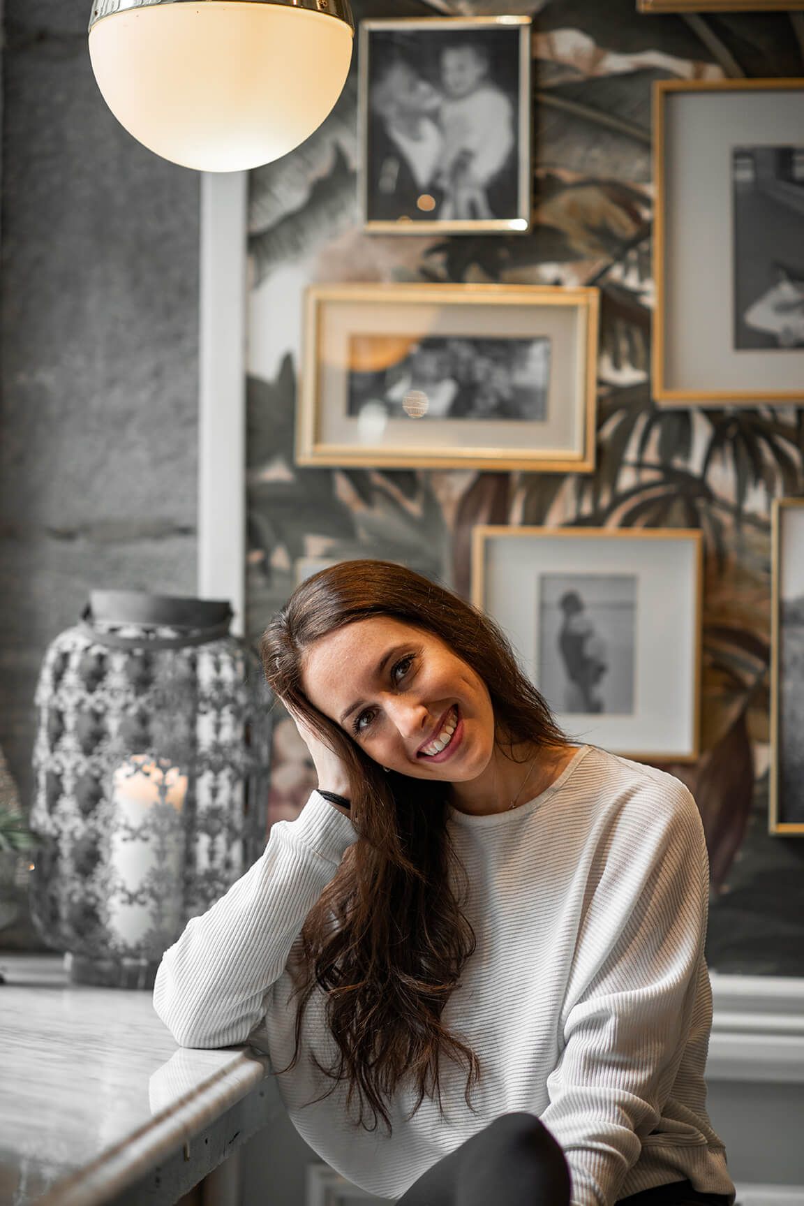 Indoor portrait session with warm lighting and vintage photo gallery wall.