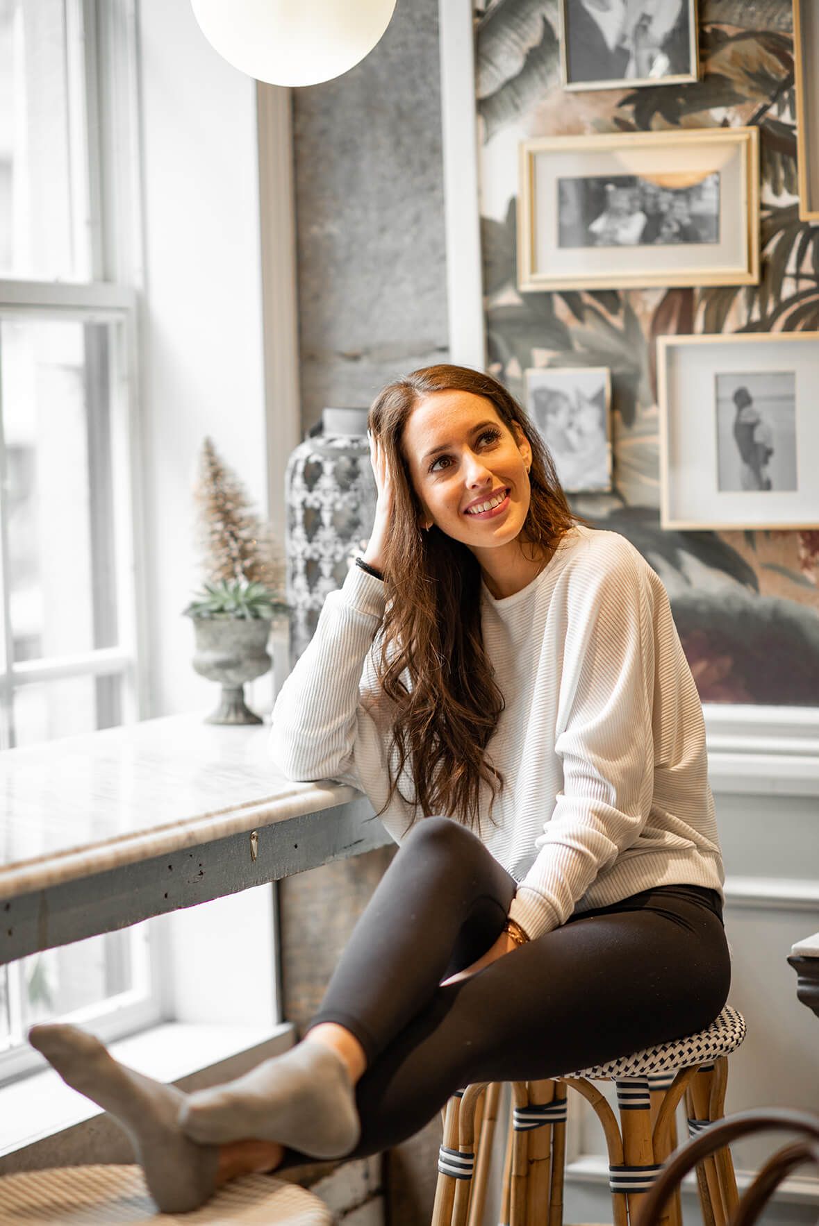 Relaxed indoor photoshoot featuring casual winter outfit against window backdrop.