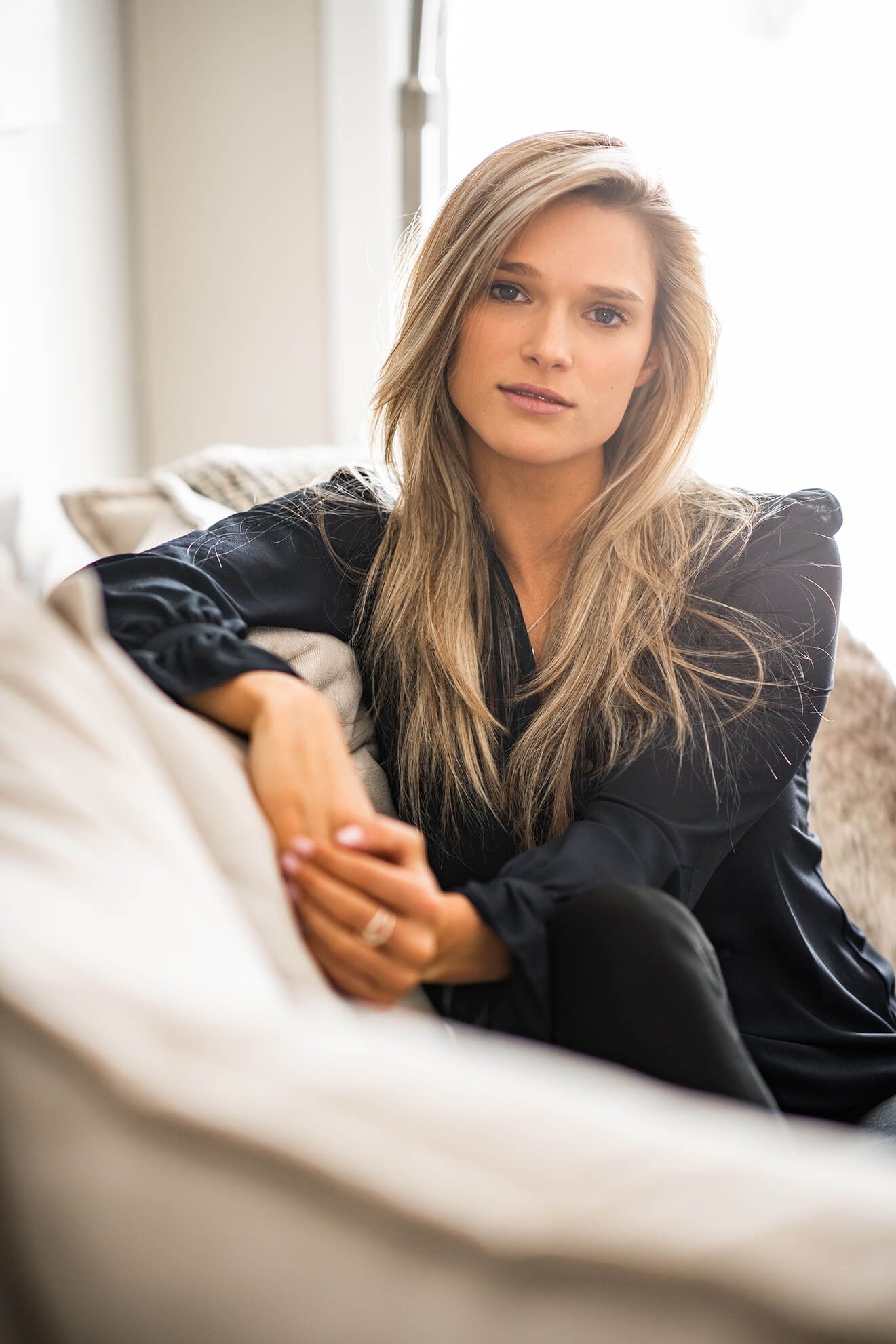 Casual portrait on beige couch with soft natural lighting.