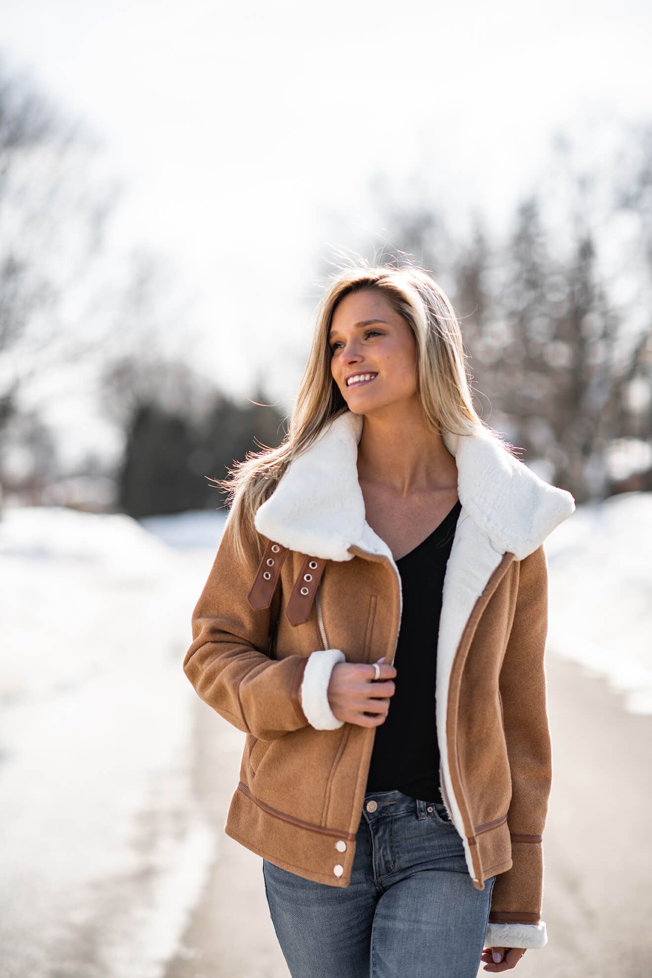 Winter fashion shoot featuring tan sherpa jacket against snowy background.