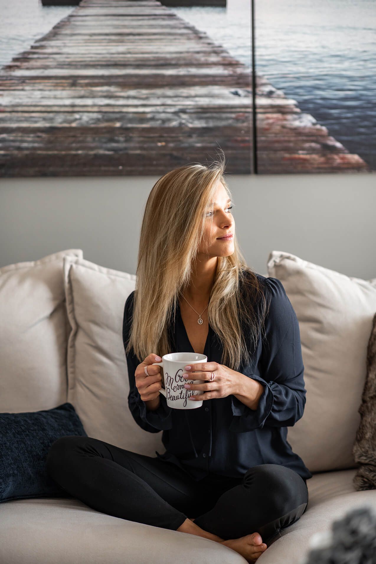 Candid photos of someone enjoying coffee while lounging on white sofa with ocean artwork.