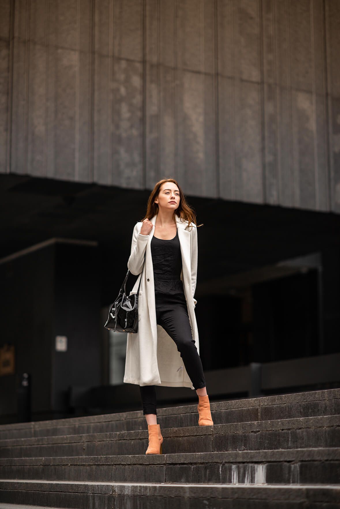 Dramatic architectural fashion photography on concrete steps with contrasting outfit details.