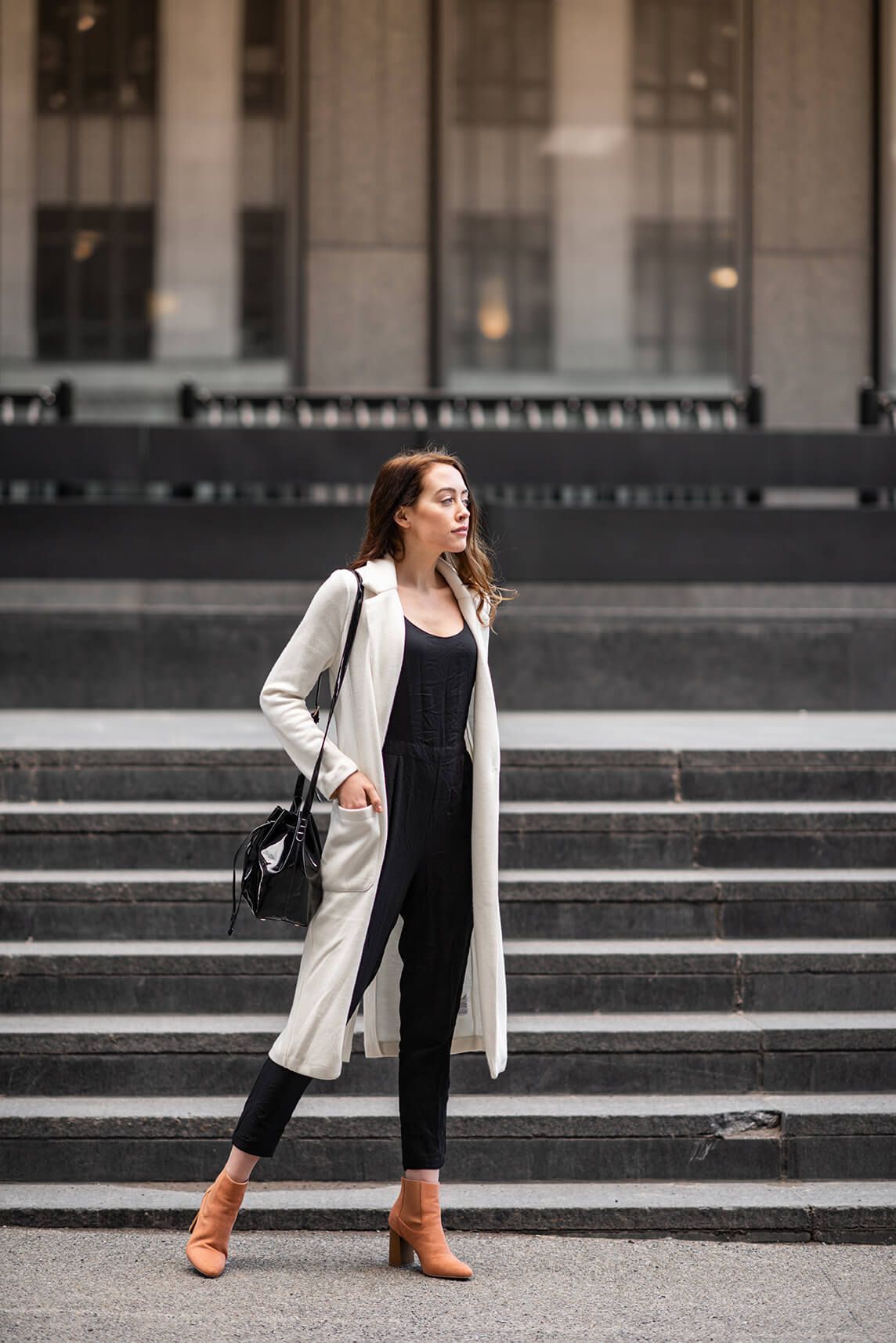 Fashion editorial shot on urban steps featuring black and white ensemble with orange boots.
