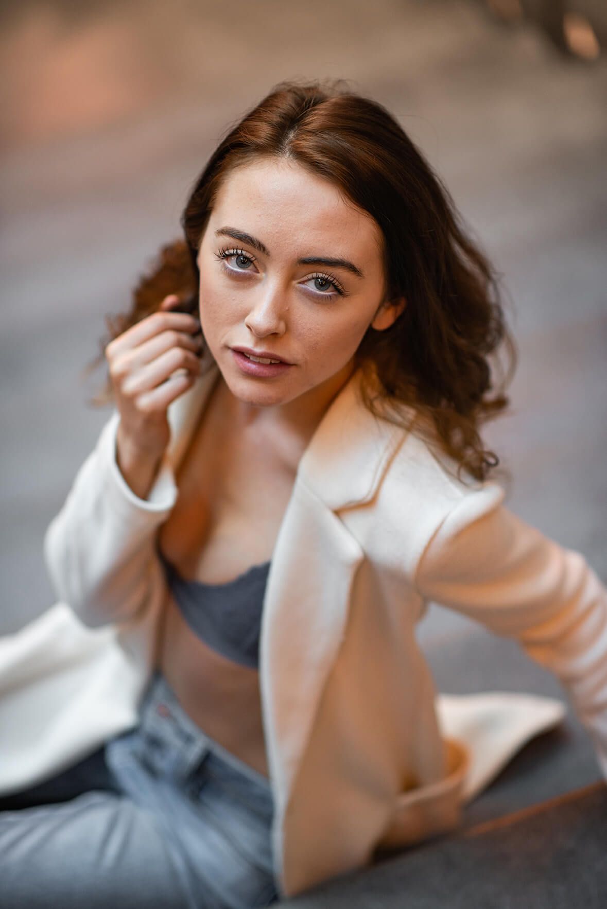 Artistic fashion portrait featuring white blazer and grey top with soft lighting.