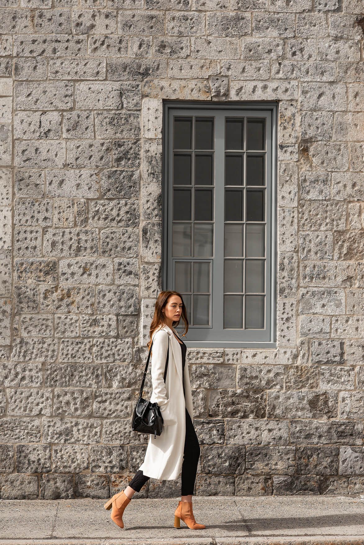 Street style photography showcasing business casual look against textured stone wall.