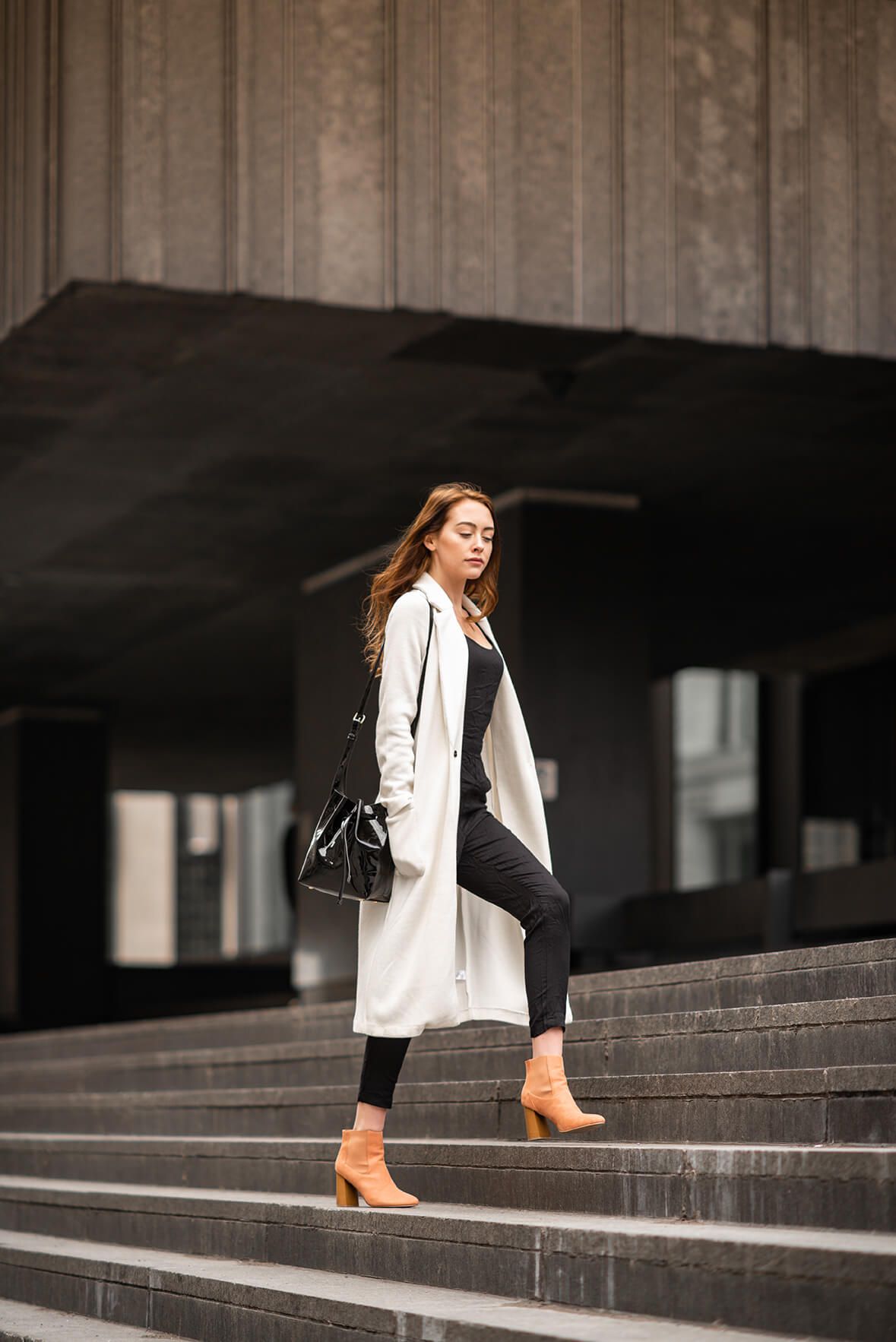 Stylish outfit featuring white blazer and boots photographed on concrete steps.