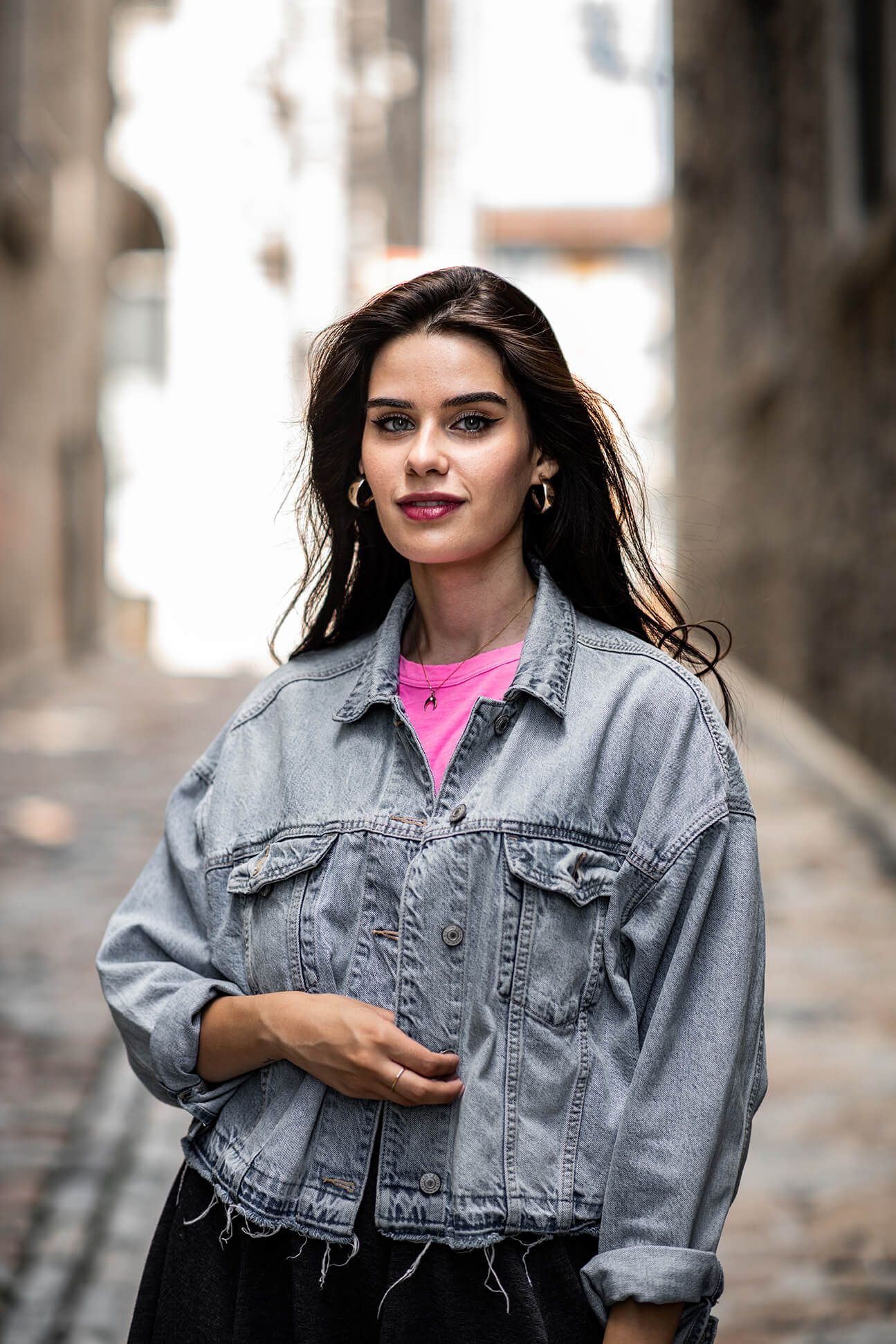 Street style portrait featuring oversized denim jacket and bright pink t-shirt.