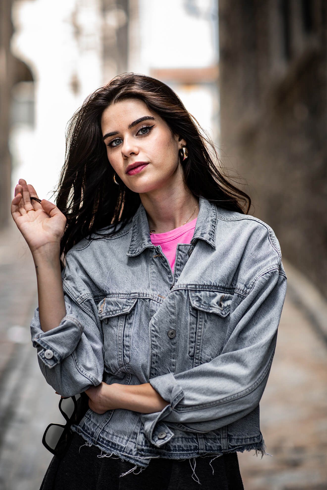 Fashion portrait with denim jacket and dramatic lighting against neutral background.