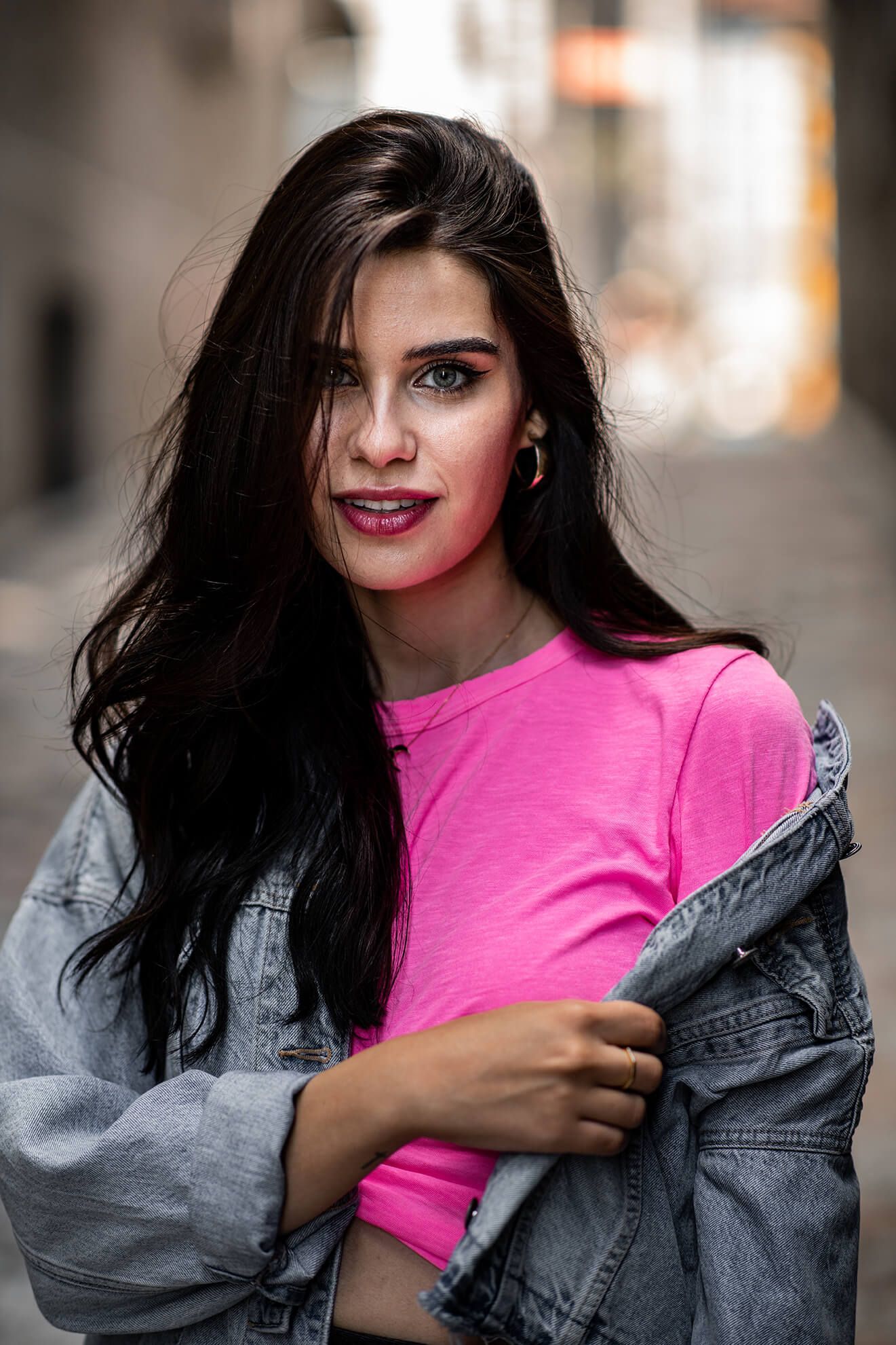 Fashion portrait featuring bright pink top and denim jacket with dramatic lighting.