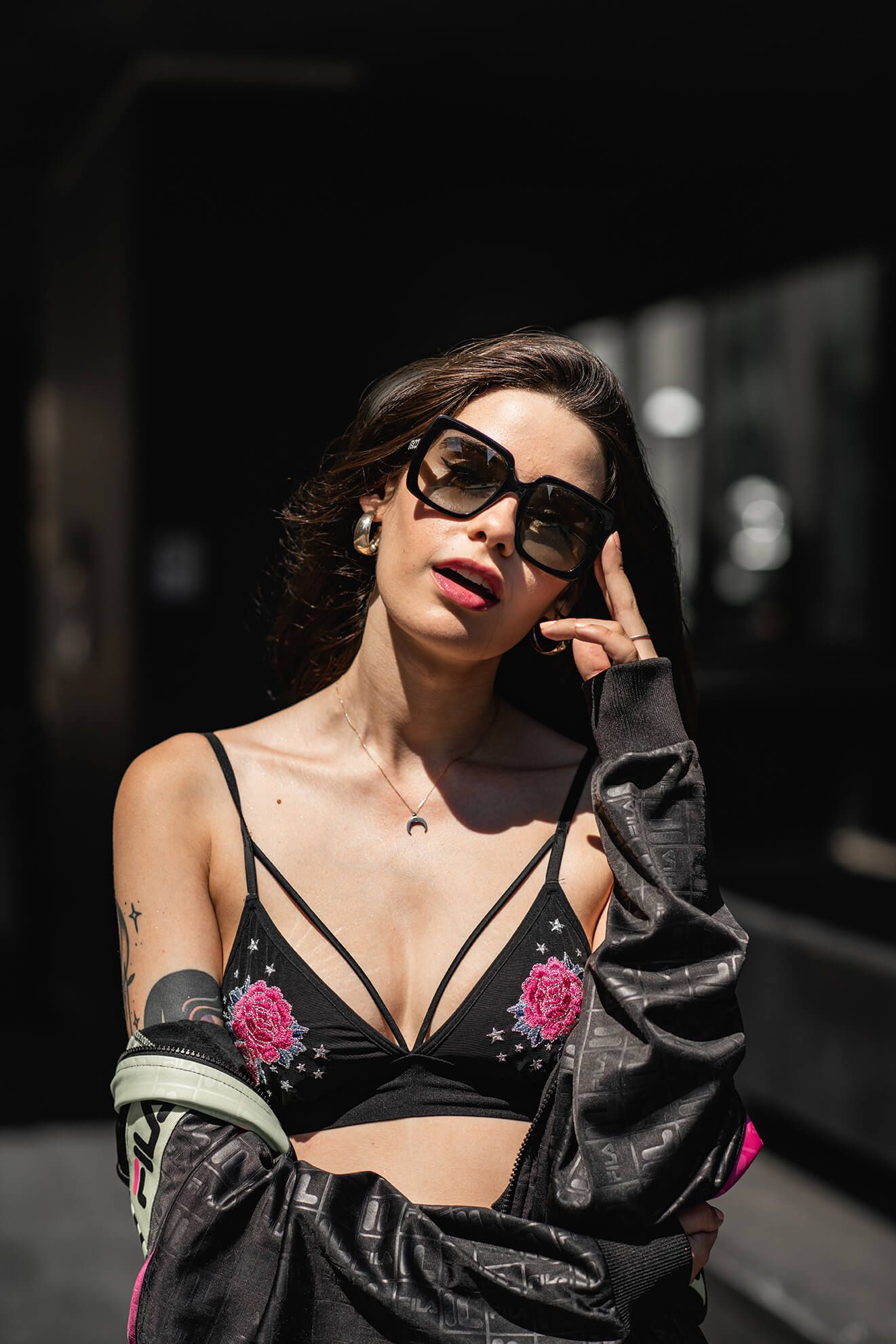 Urban fashion shot with statement sunglasses and strappy black bralette.