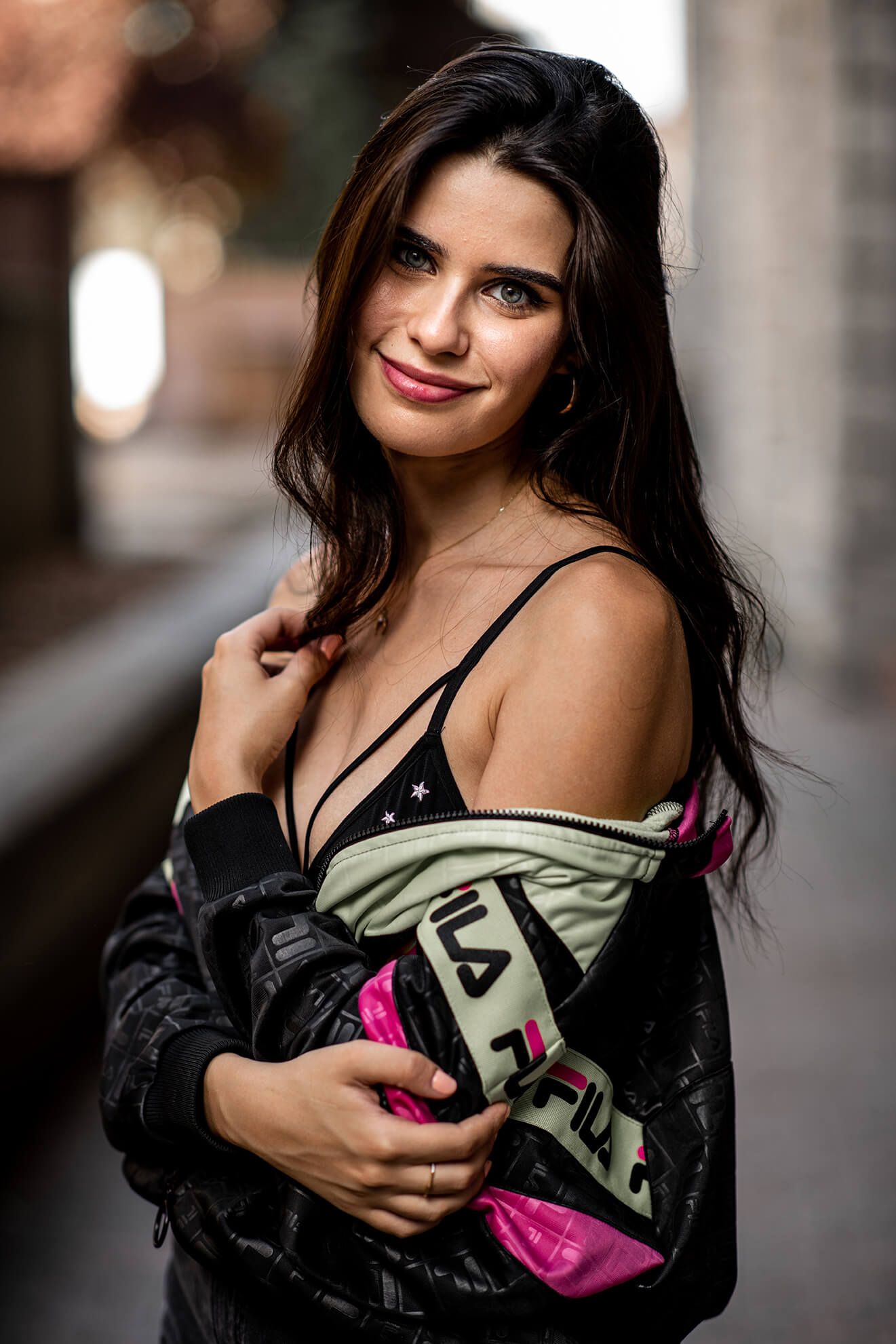 A person poses with a sports drink bottle in an urban setting wearing athletic wear.