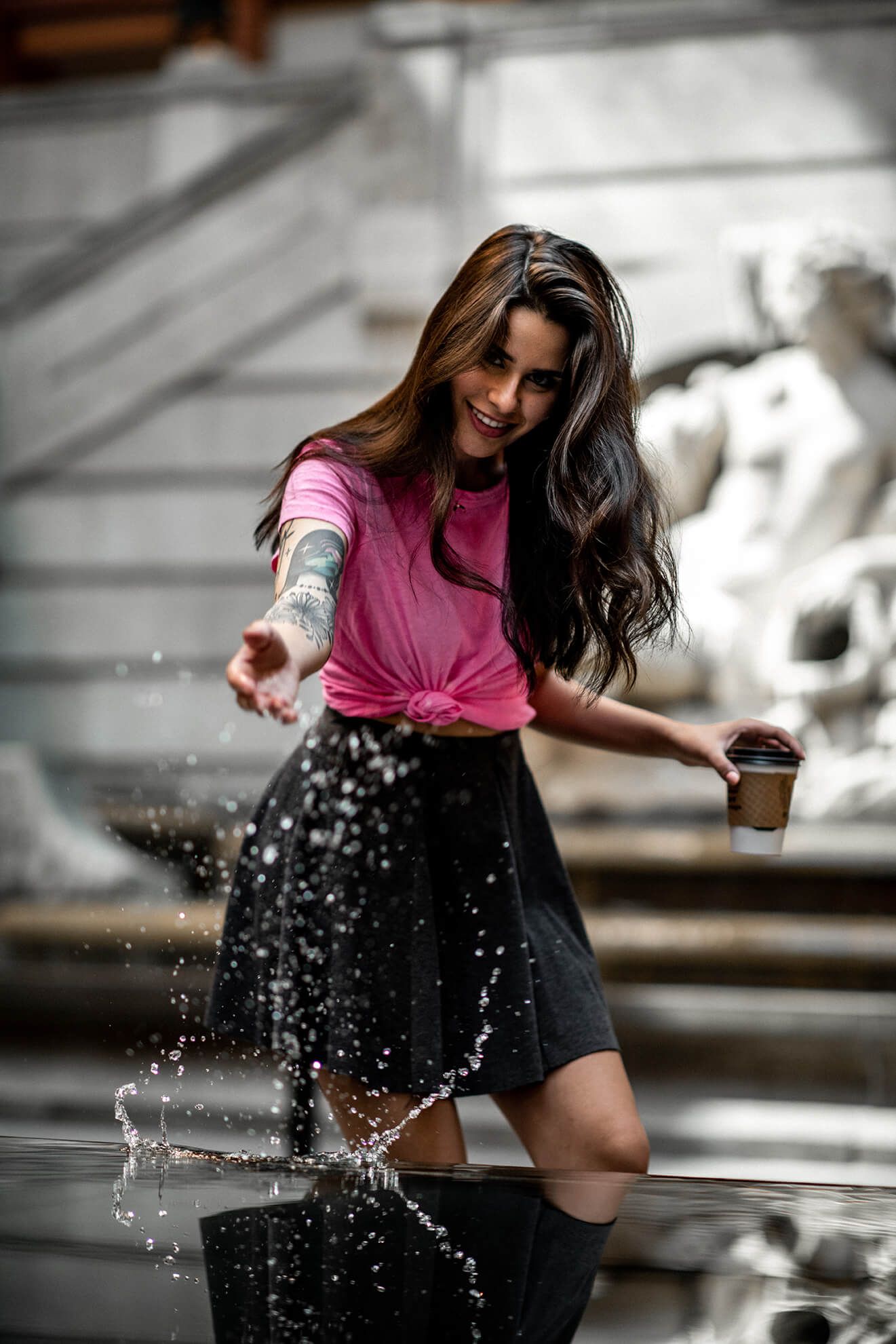 A person in pink and black creates dynamic water splashes during a photoshoot.