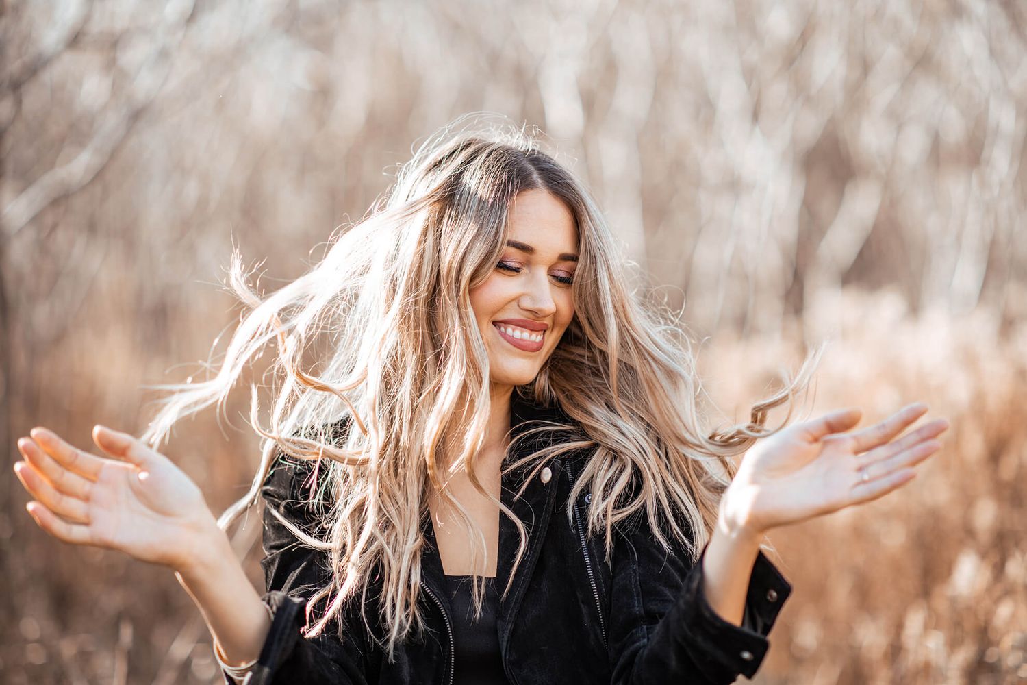 Candid shots of a woman dancing and expressing joy in an autumn woodland setting.