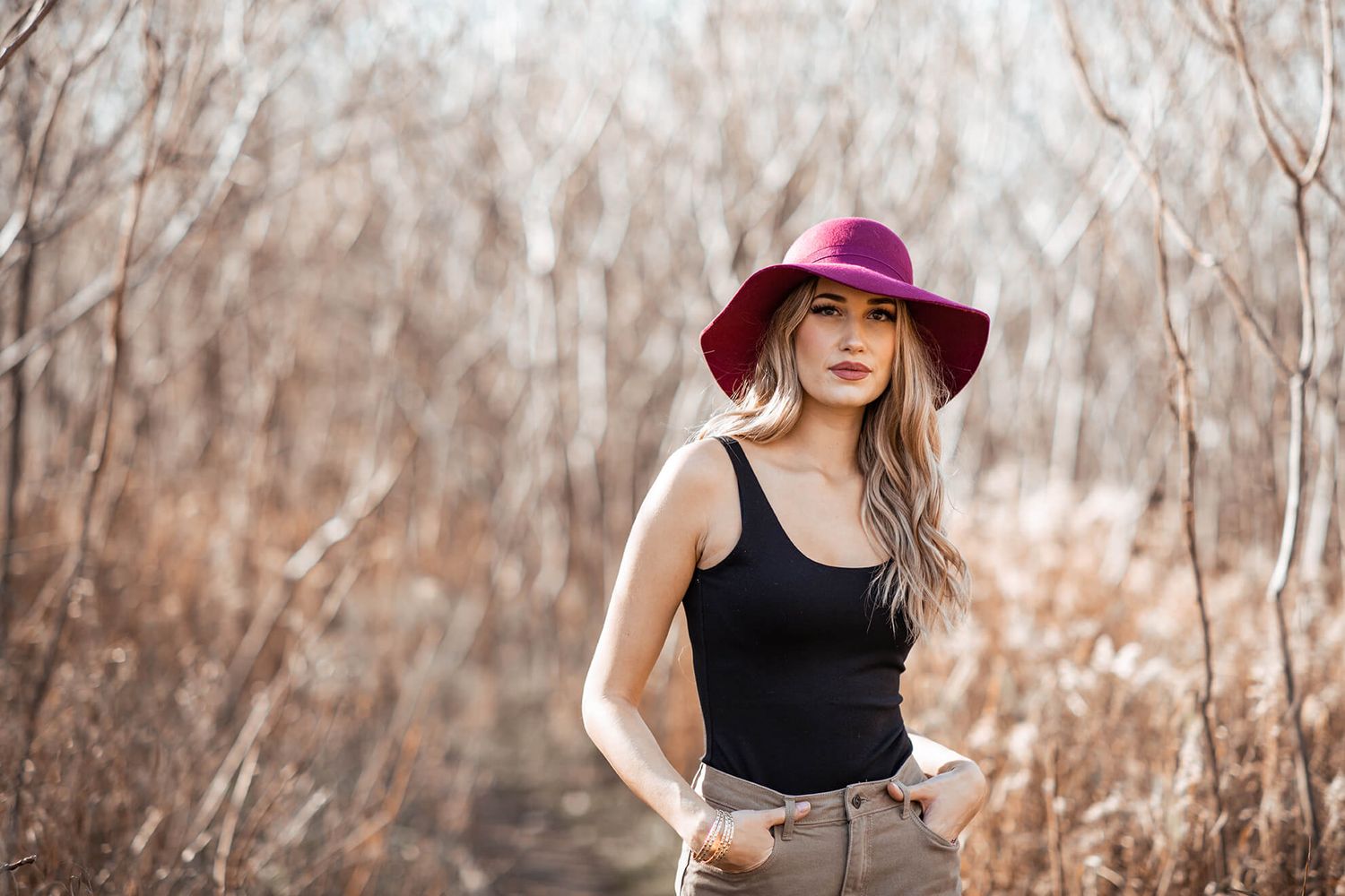 Lifestyle fashion photo with burgundy hat and black top in natural setting.