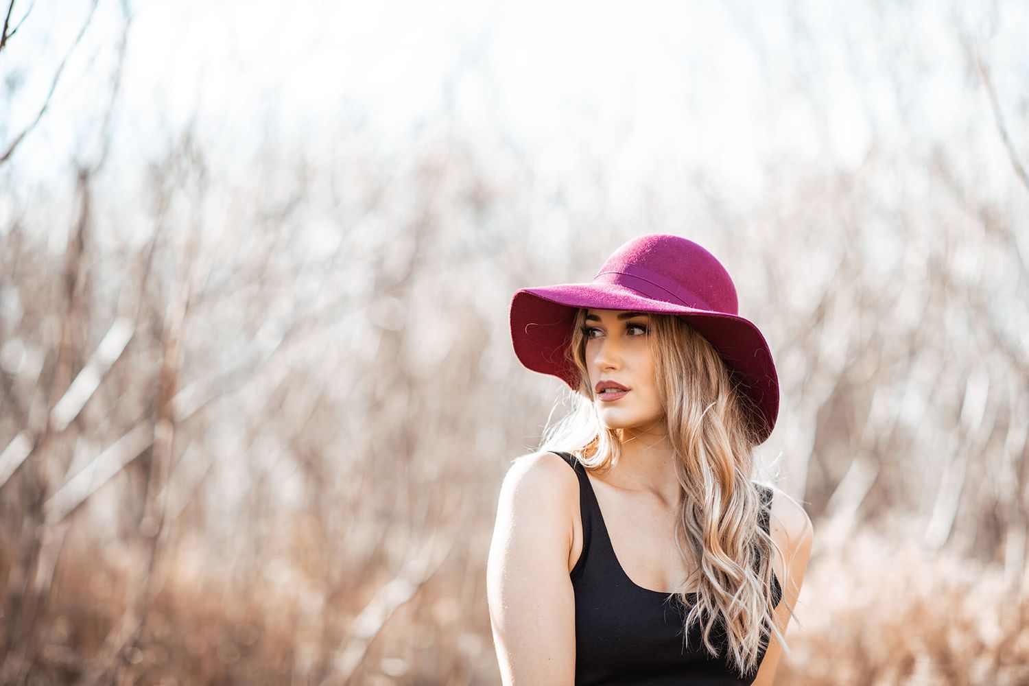 Artistic fashion photo with burgundy hat against blurred autumn background.