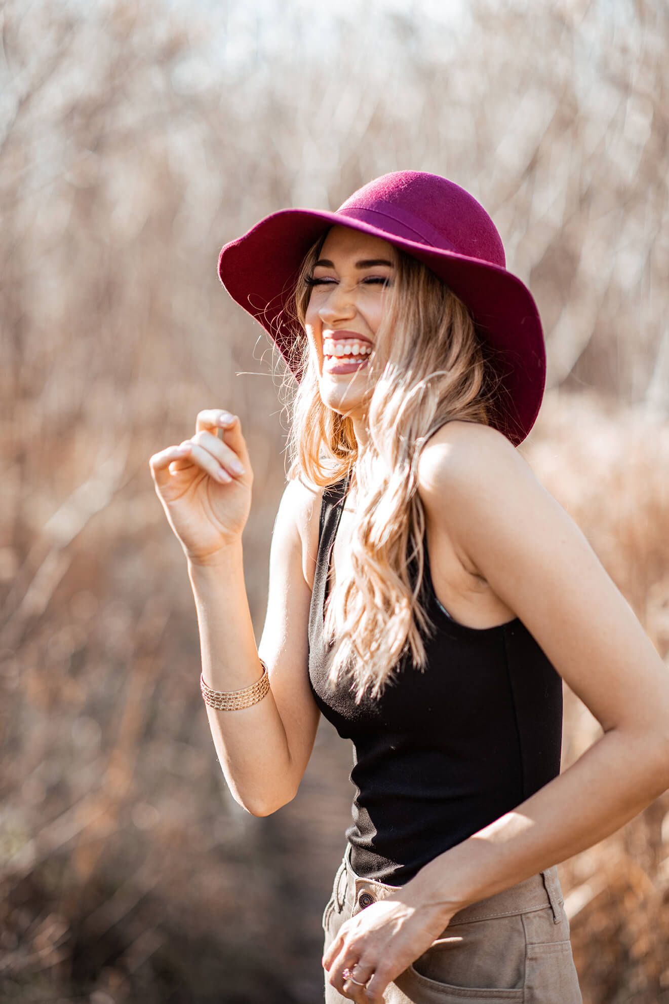 Candid fashion portrait with burgundy hat and black sleeveless top in autumn setting.
