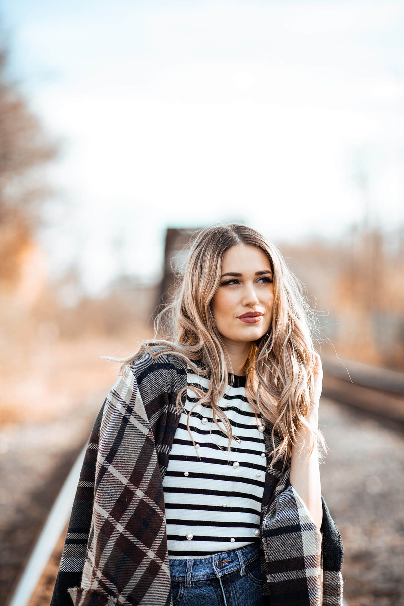 Casual street style with striped top and plaid scarf in warm tones.
