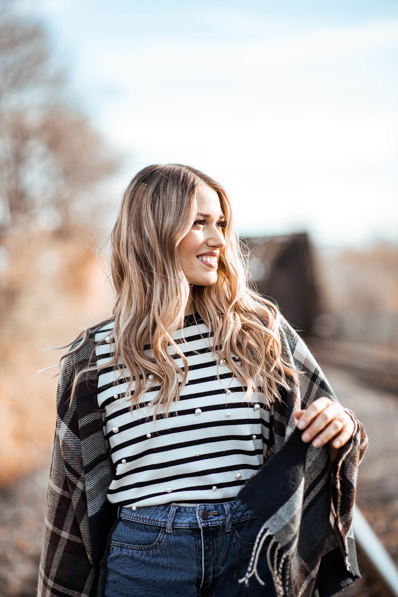 Candid fashion portrait with striped shirt and plaid scarf in natural lighting.