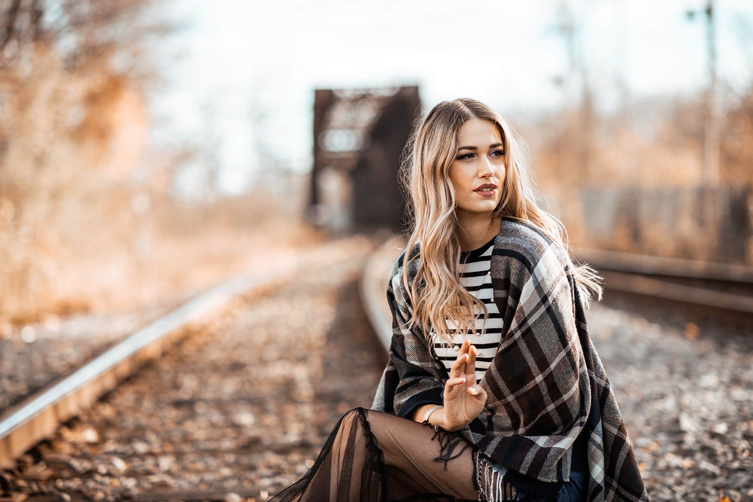 Railroad track fashion shoot featuring plaid wrap and striped top.