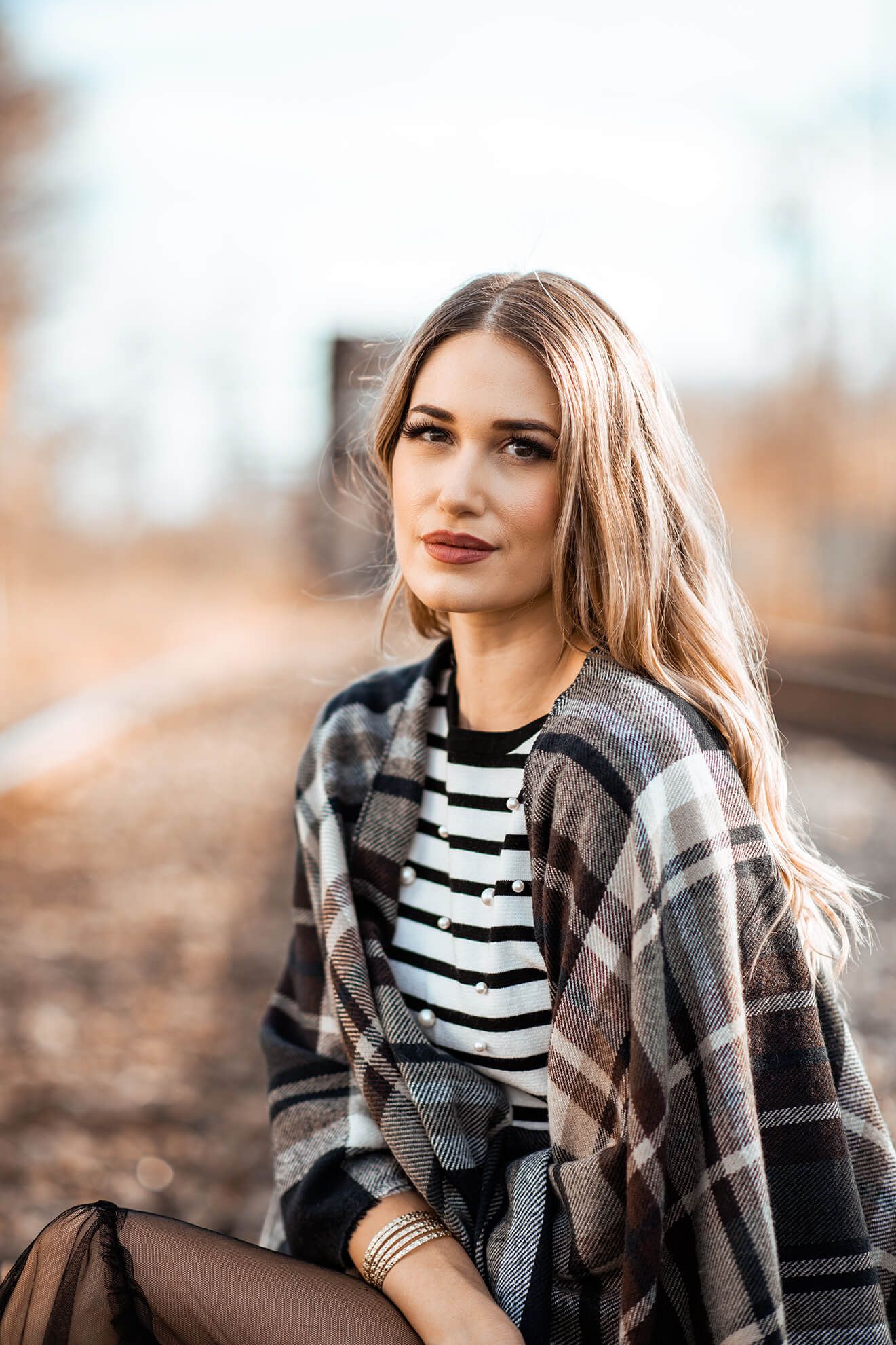 Autumn fashion portrait featuring plaid wrap and classic striped shirt.