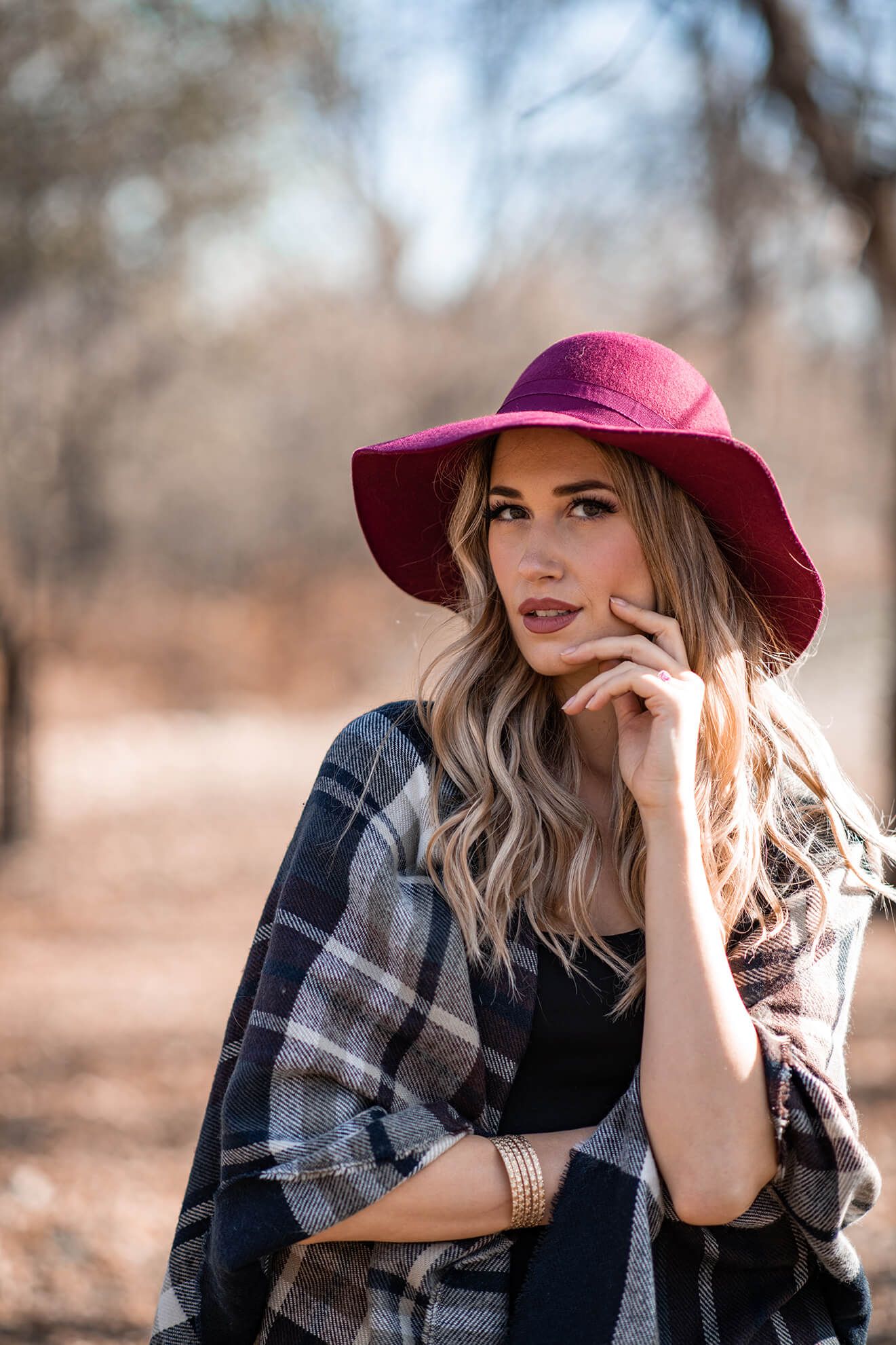 Autumn portrait with burgundy hat and plaid scarf in natural setting.