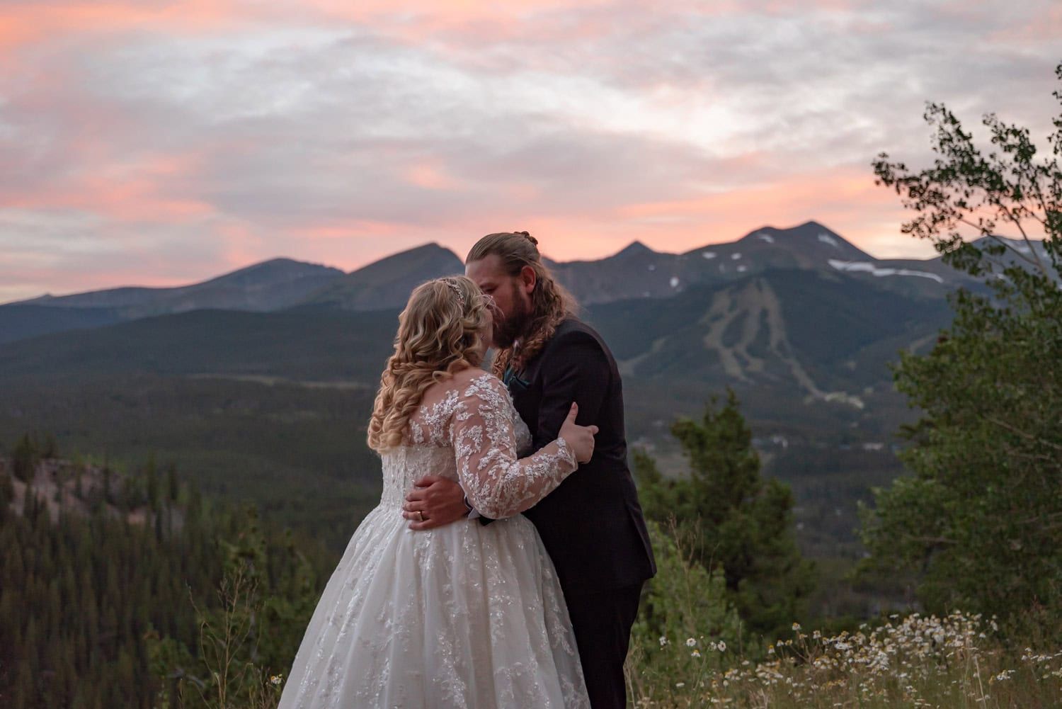 Stunning mountain landscape at sunset with pink and orange clouds over snow-capped peaks.