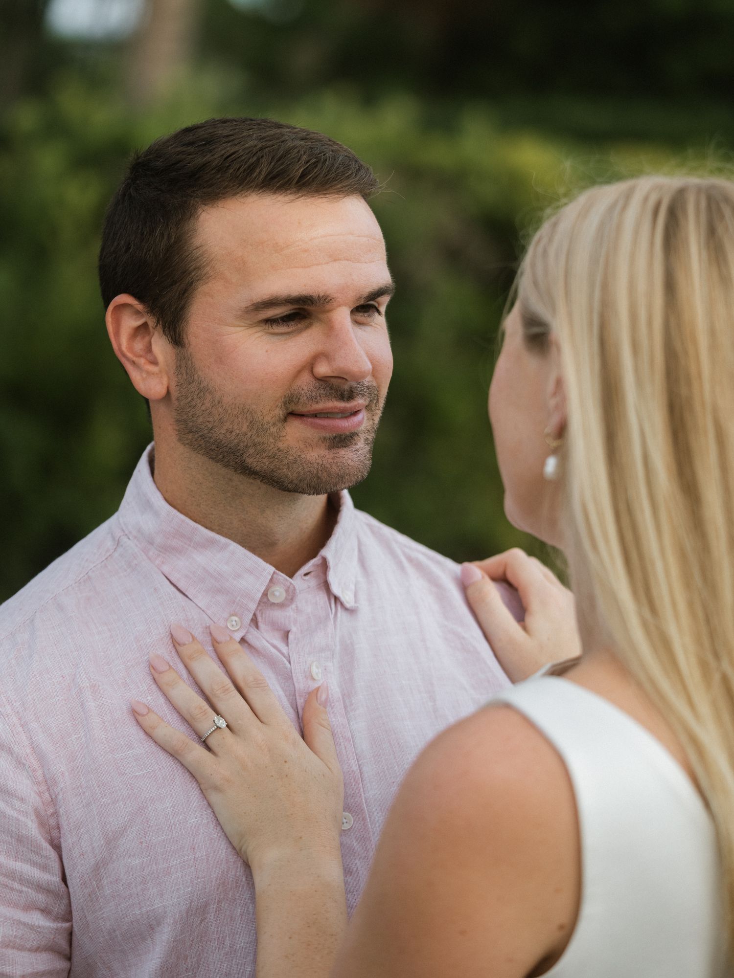 A tender moment between a couple during their engagement photoshoot in a garden setting.