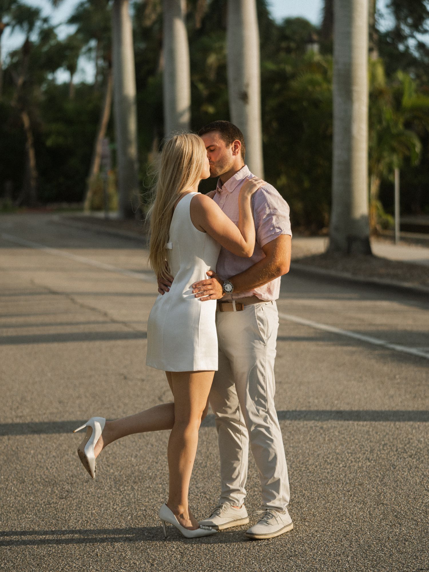 Dancing couple's feet and lower bodies moving gracefully among palm trees on a paved surface.