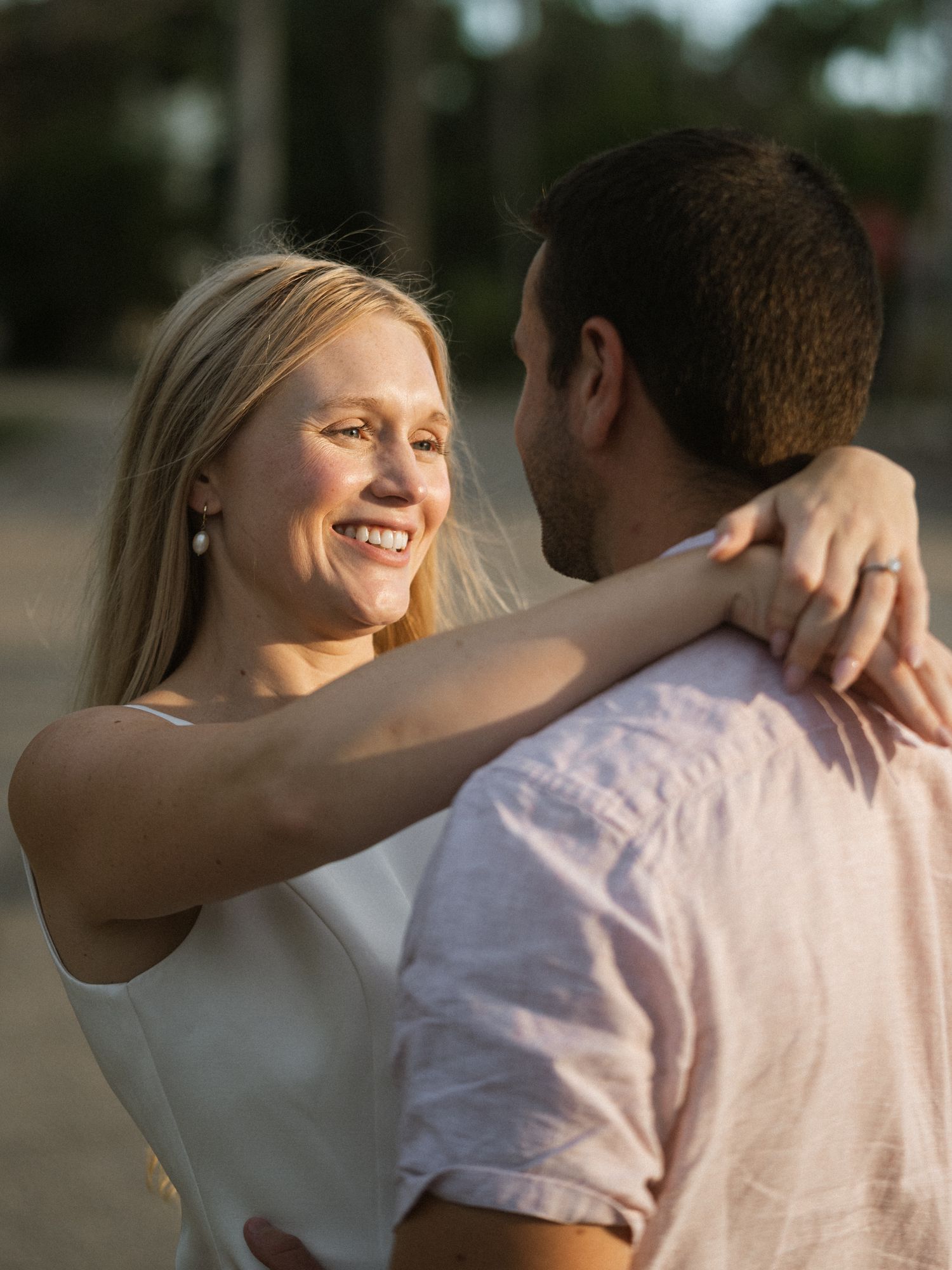 Couple embracing in warm sunset light with natural outdoor backdrop.