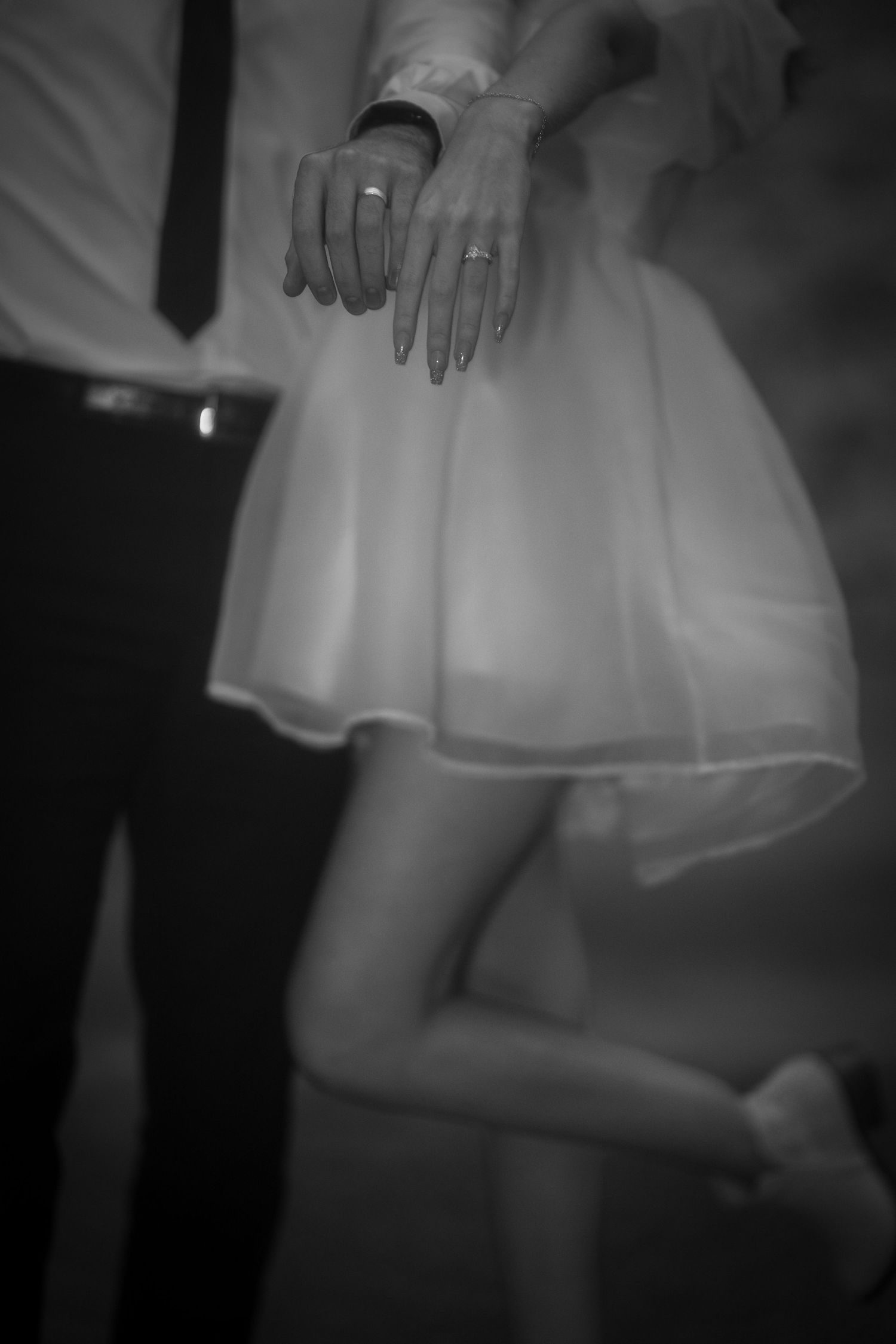 Black and white detail shots of formal dress and hands with wedding rings.