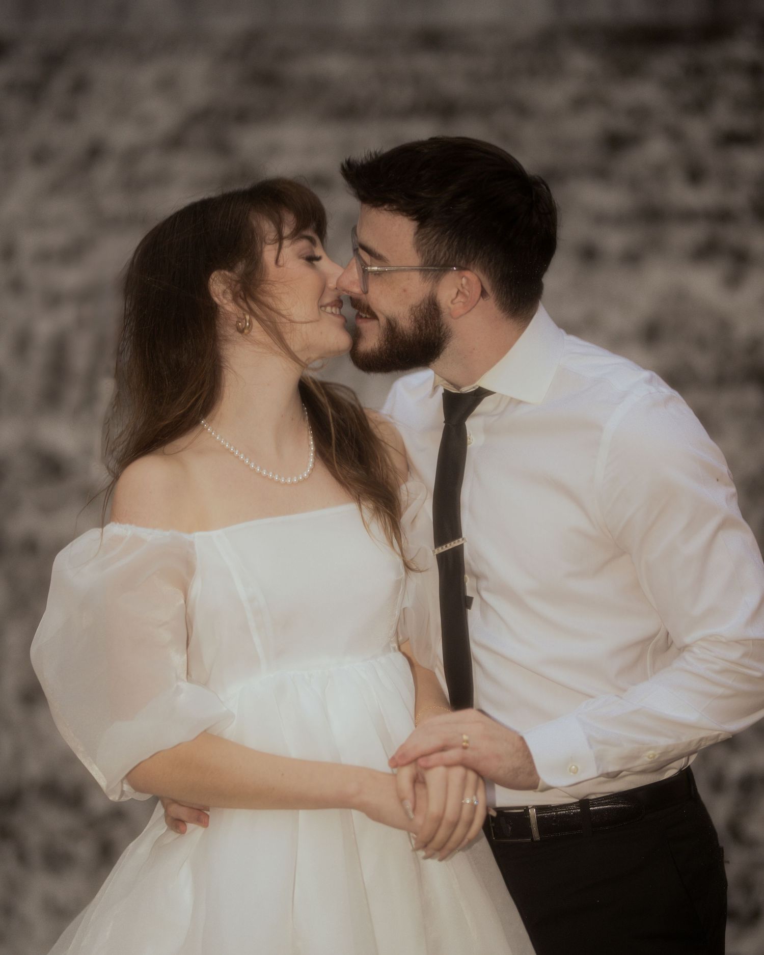 A romantic couple in wedding attire share intimate moments in a series of tender poses against a textured wall.
