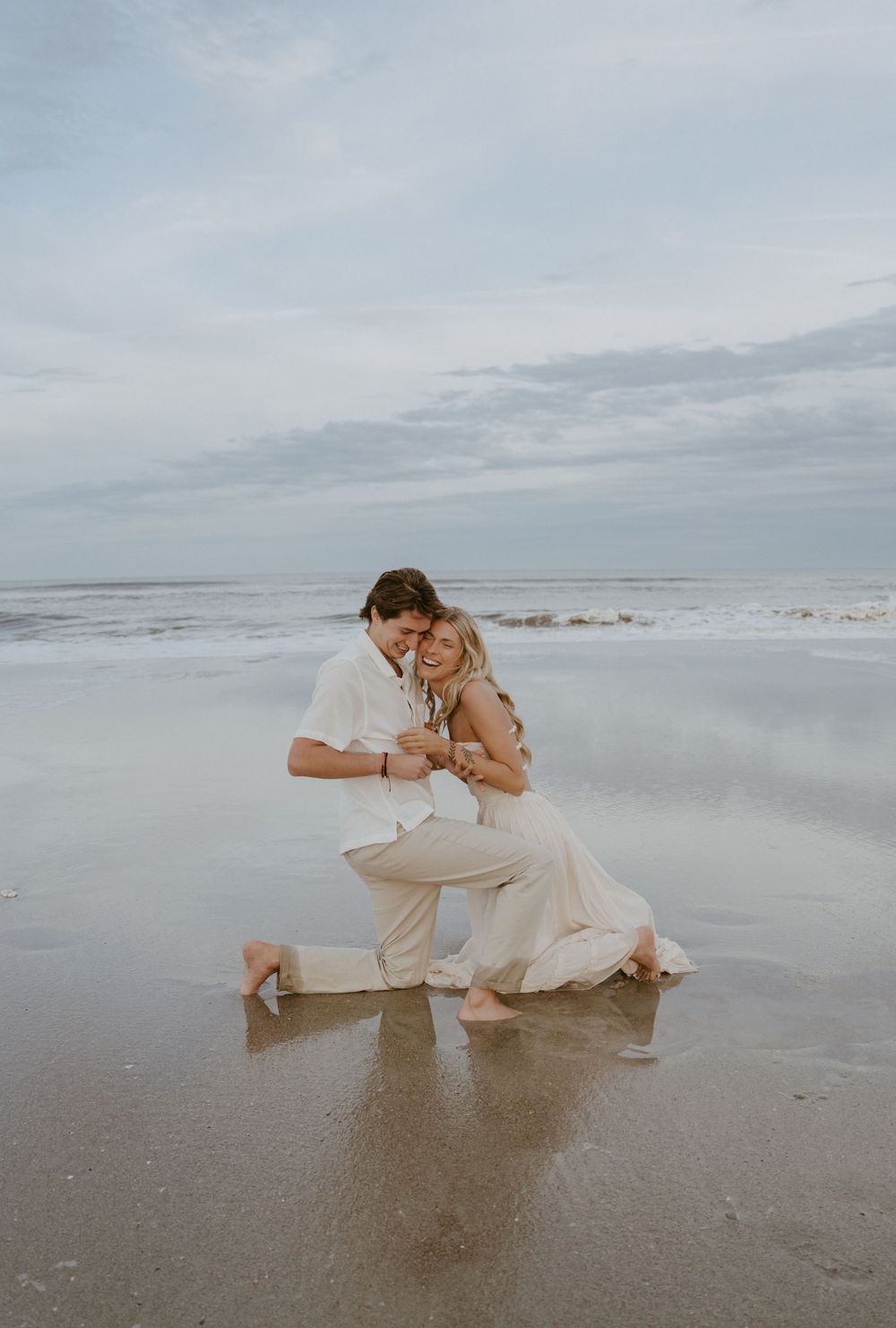 Couple in white outfits sharing romantic moments on a misty beach shoreline in a sequence of artistic poses.