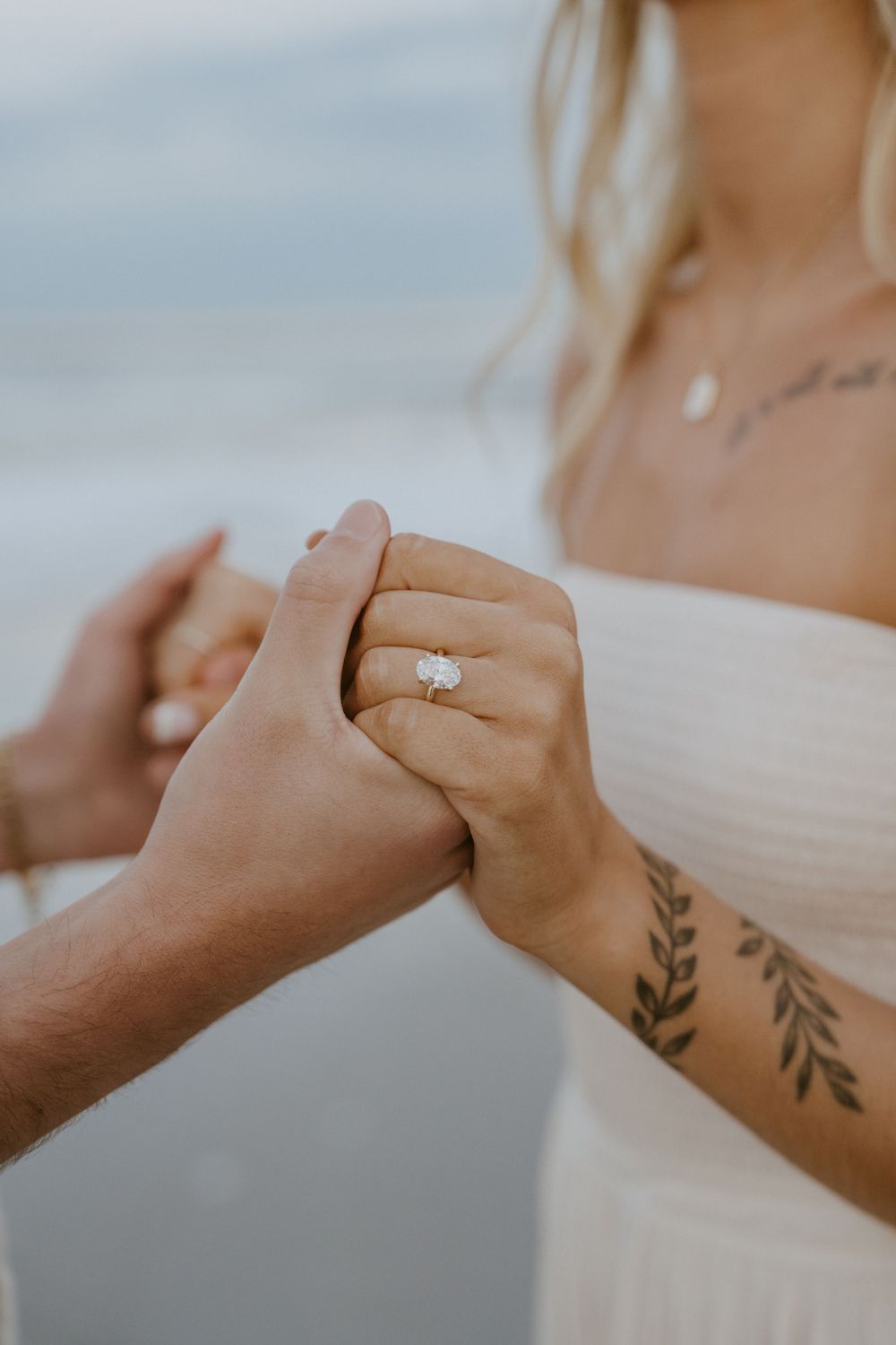 Close-up shots of hands with delicate tattoos and an engagement ring against a soft, blurred background.