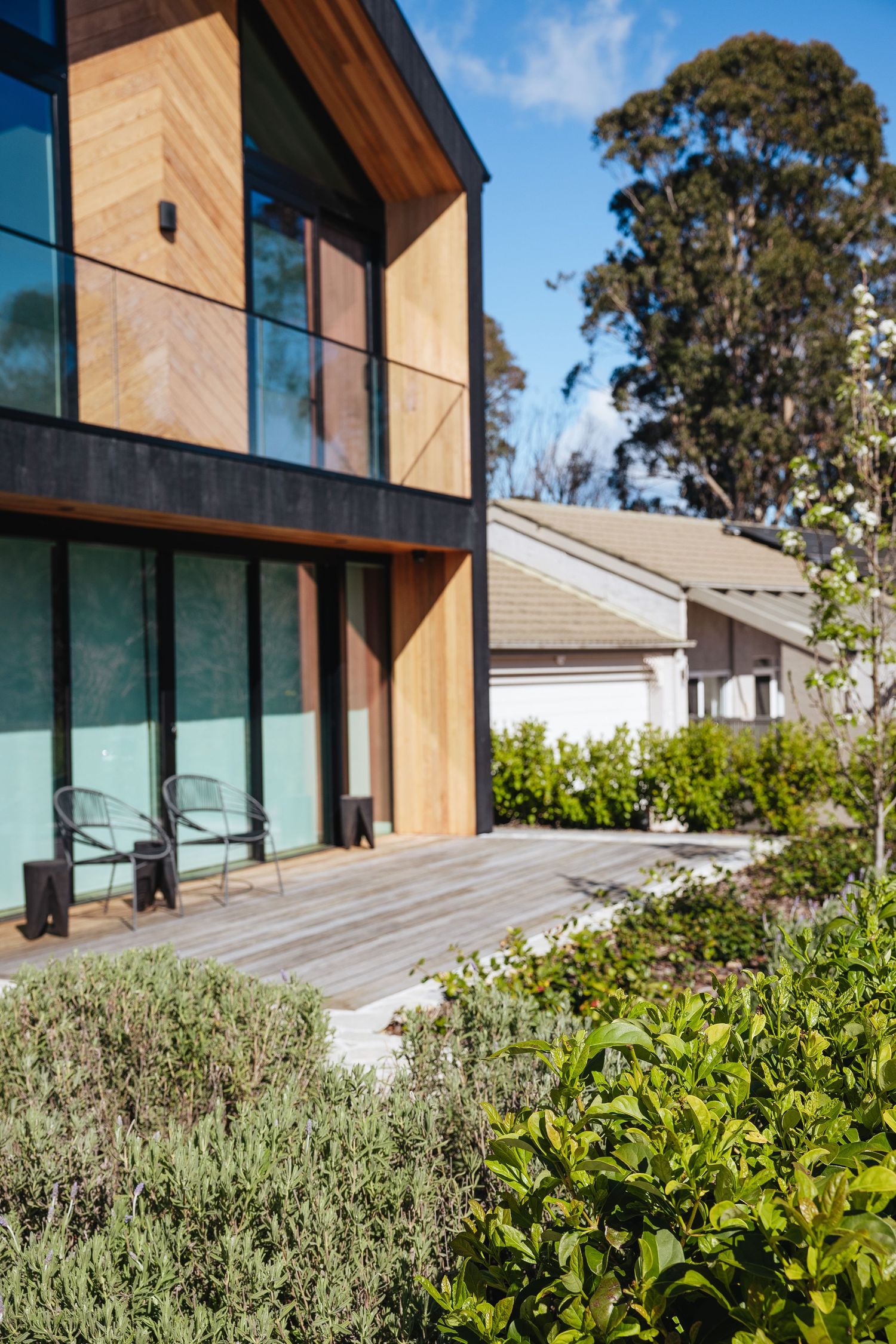 Modern wooden and glass house exterior with landscaped garden features sloped design and natural materials.
