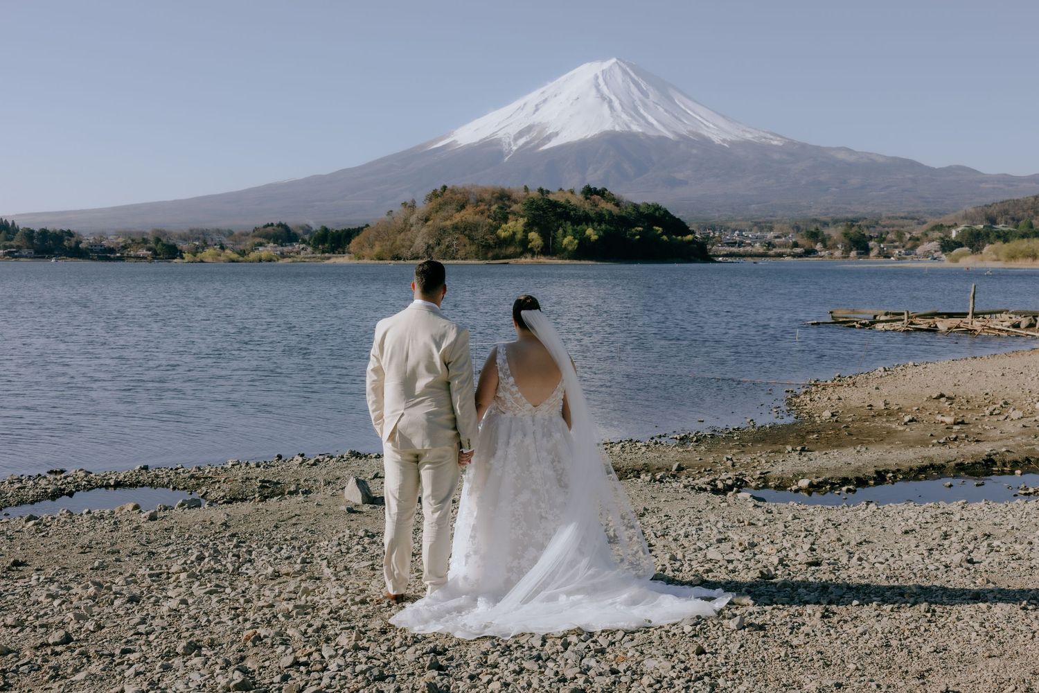 Wedding couple poses near Mount Fuji with stunning lake and mountain views in Japan.