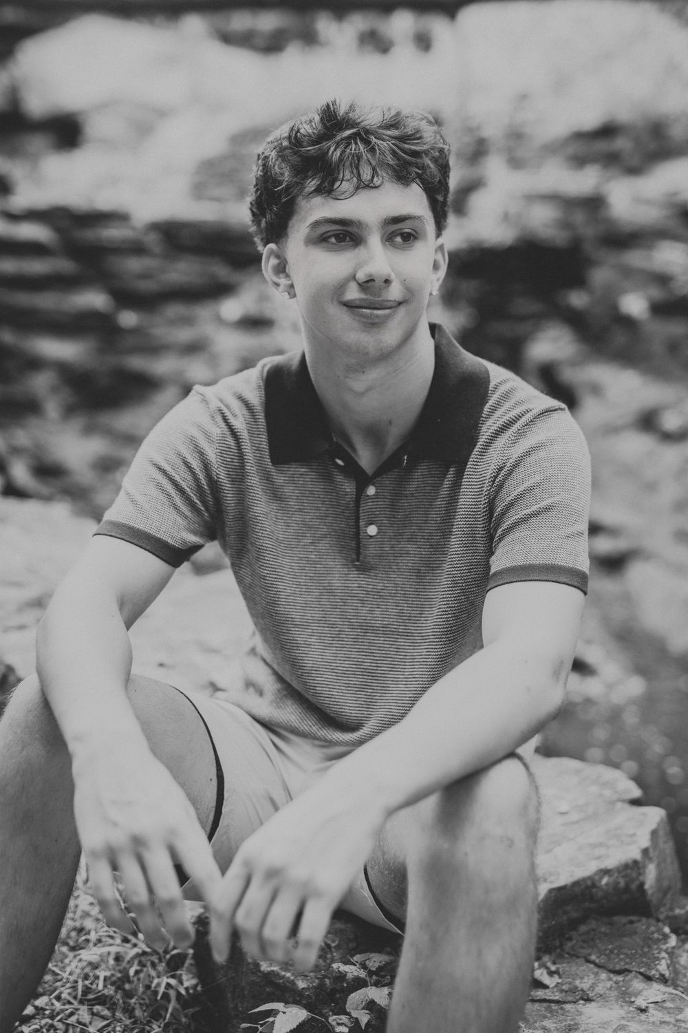 Black and white portrait series showing a young person in a polo shirt sitting casually outdoors.